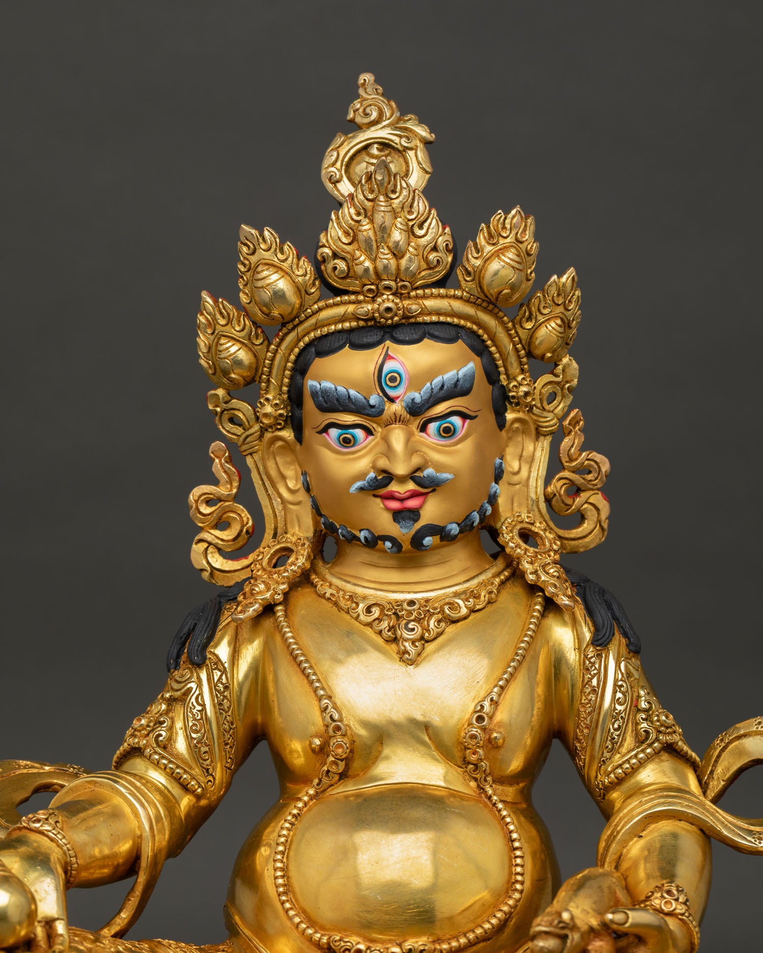 Close up Dzambhala Buddhist statue showing gold painted face intricate Nepalese craftsmanship
