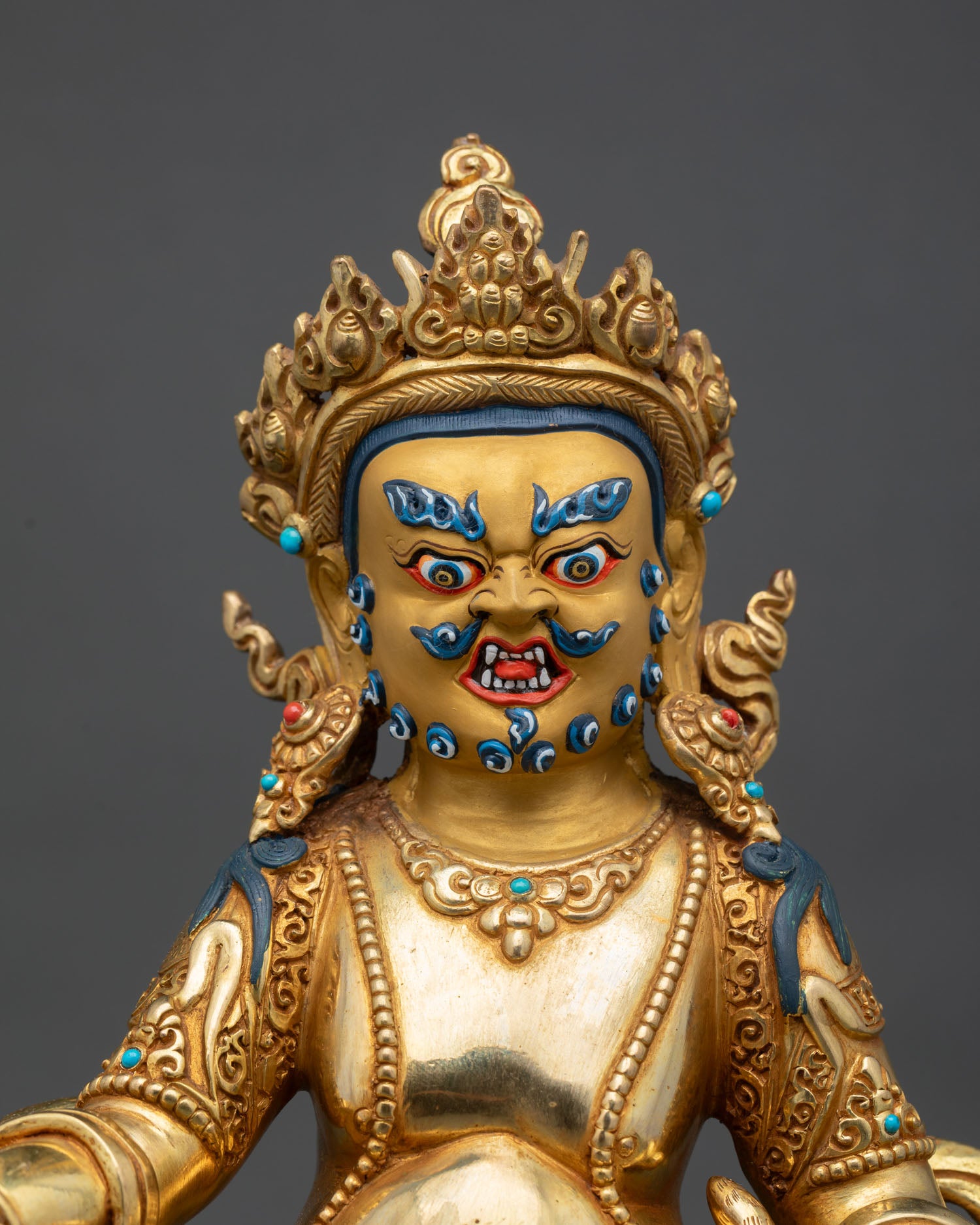 Close up Dzambhala fierce compassionate face, detail gold fire gilded copper statue, Himalayan craftsmanship
