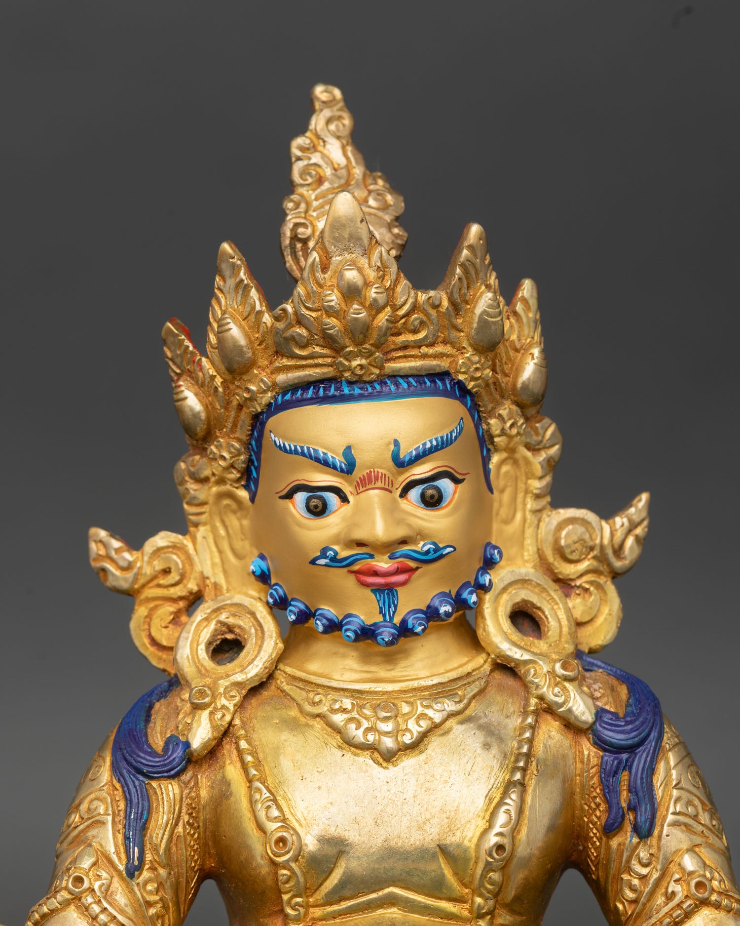 Close up Dzambhala statue jeweled crown detailed ornaments gold gilded face sacred Buddhist craftsmanship