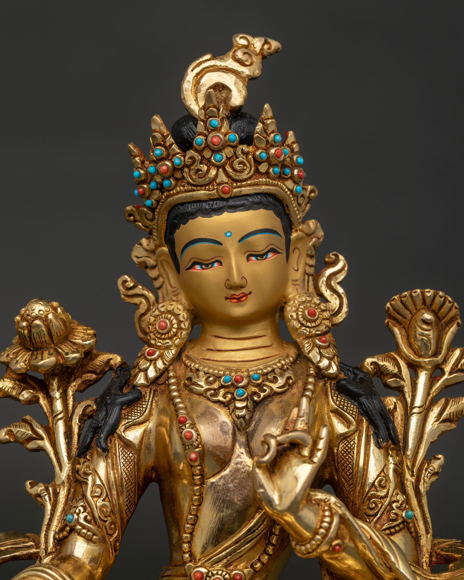 Close up Green Tara Buddhist statue with gold painted face and semi precious stones.