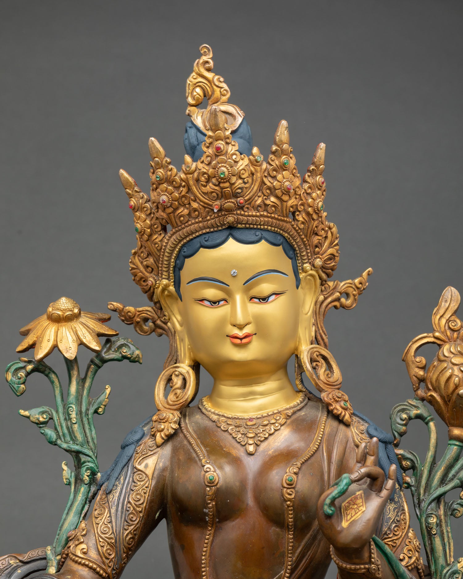 Close up Green Tara face with gold painted expression and five jewel crown Newari artisan Nepal copper goddess statue