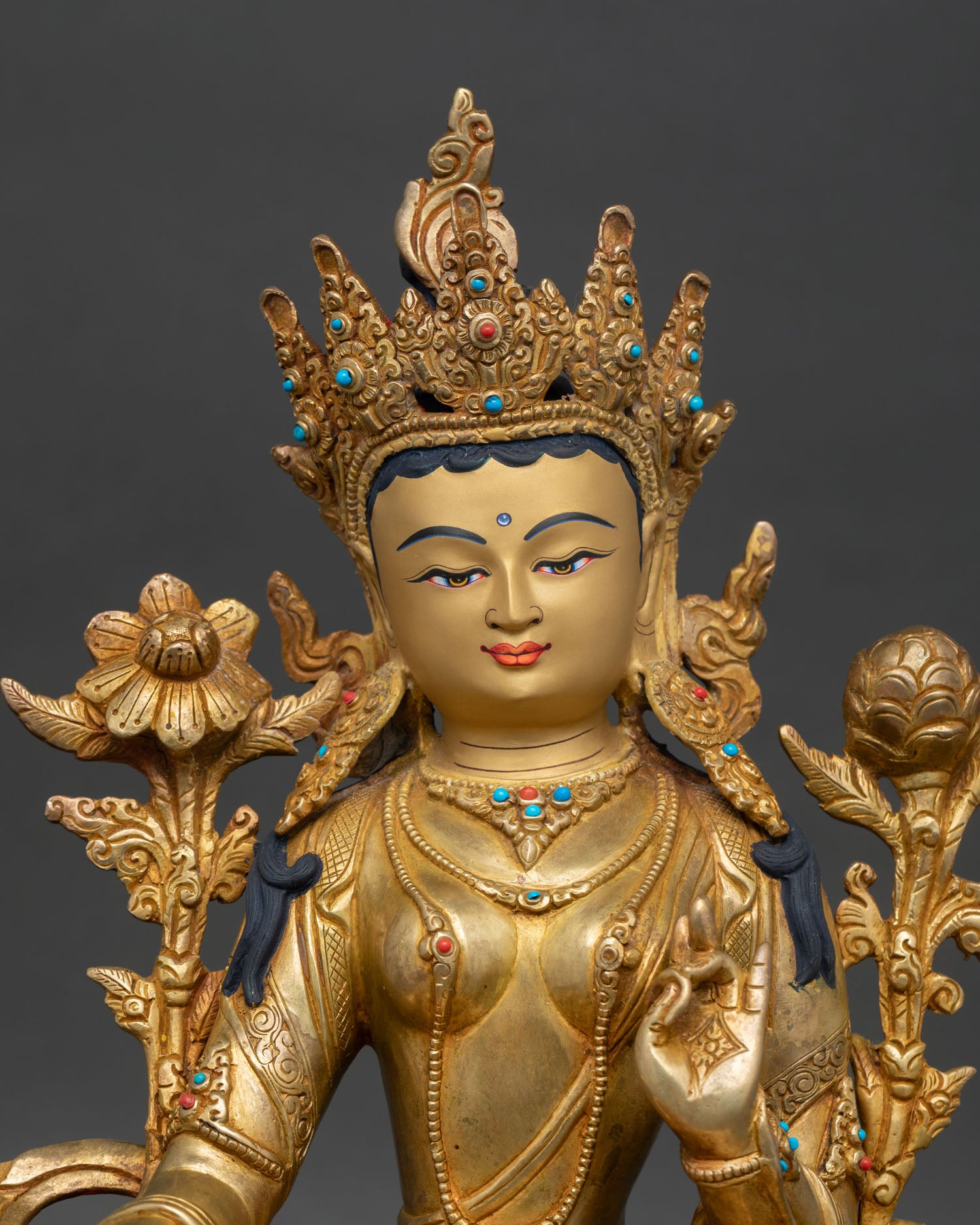 Close-up Green Tara gold-painted face seated in lotus lalitasana posture, Buddhist goddess of swift compassion art