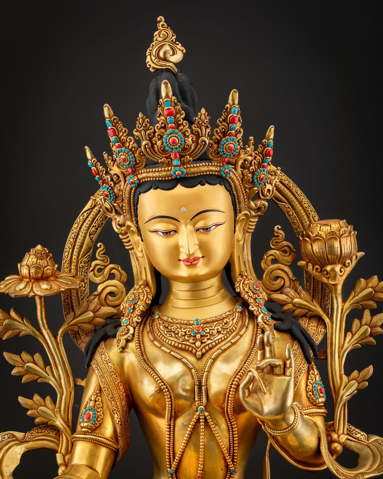 Close up Green Tara serene gold painted face with detailed crown turquoise ornaments and intricate Himalayan craftsmanship