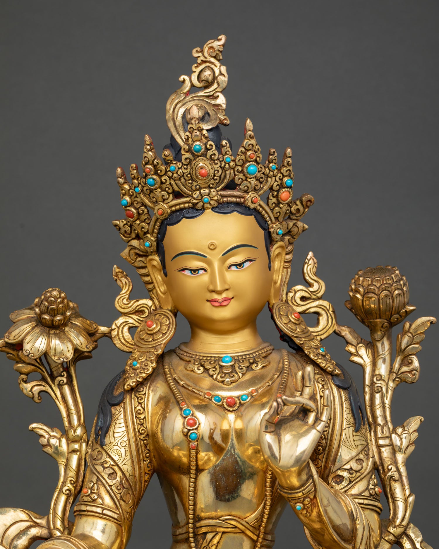 Close up Green Tara serene gold painted face with intricate crown turquoise and coral stone ornaments Himalayan craftsmanship detail