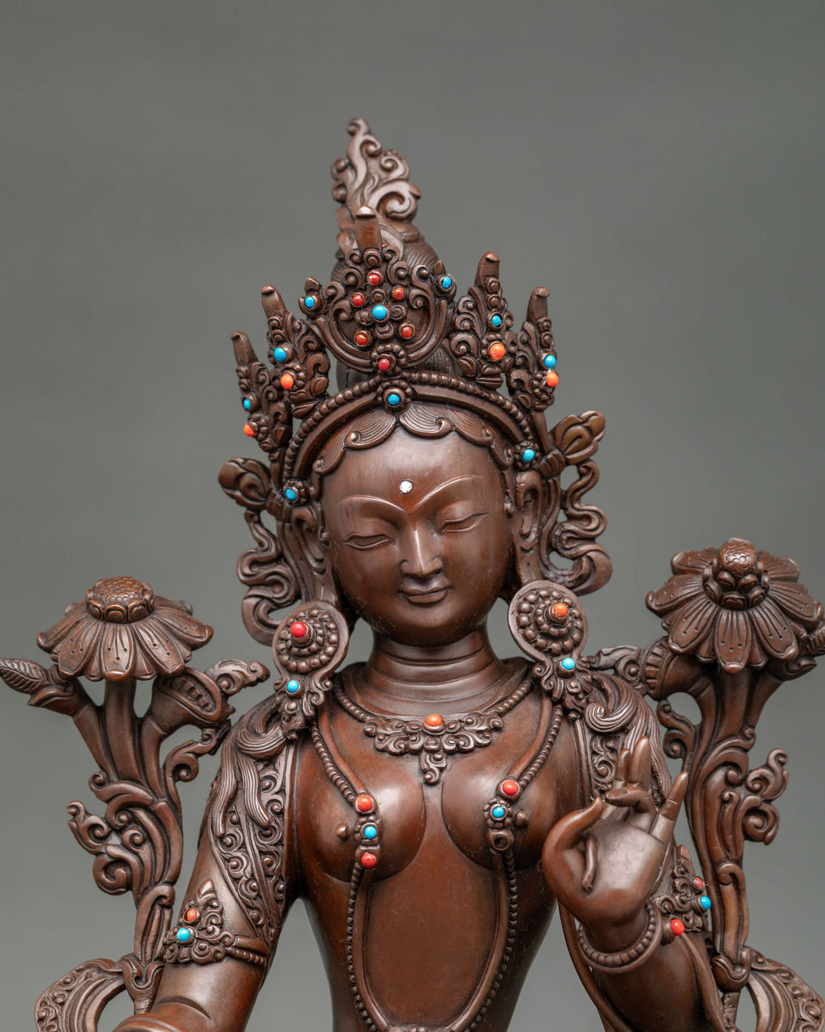 Close up Green Tara Statue gently closed eyes, five jewel crown and gemstone details