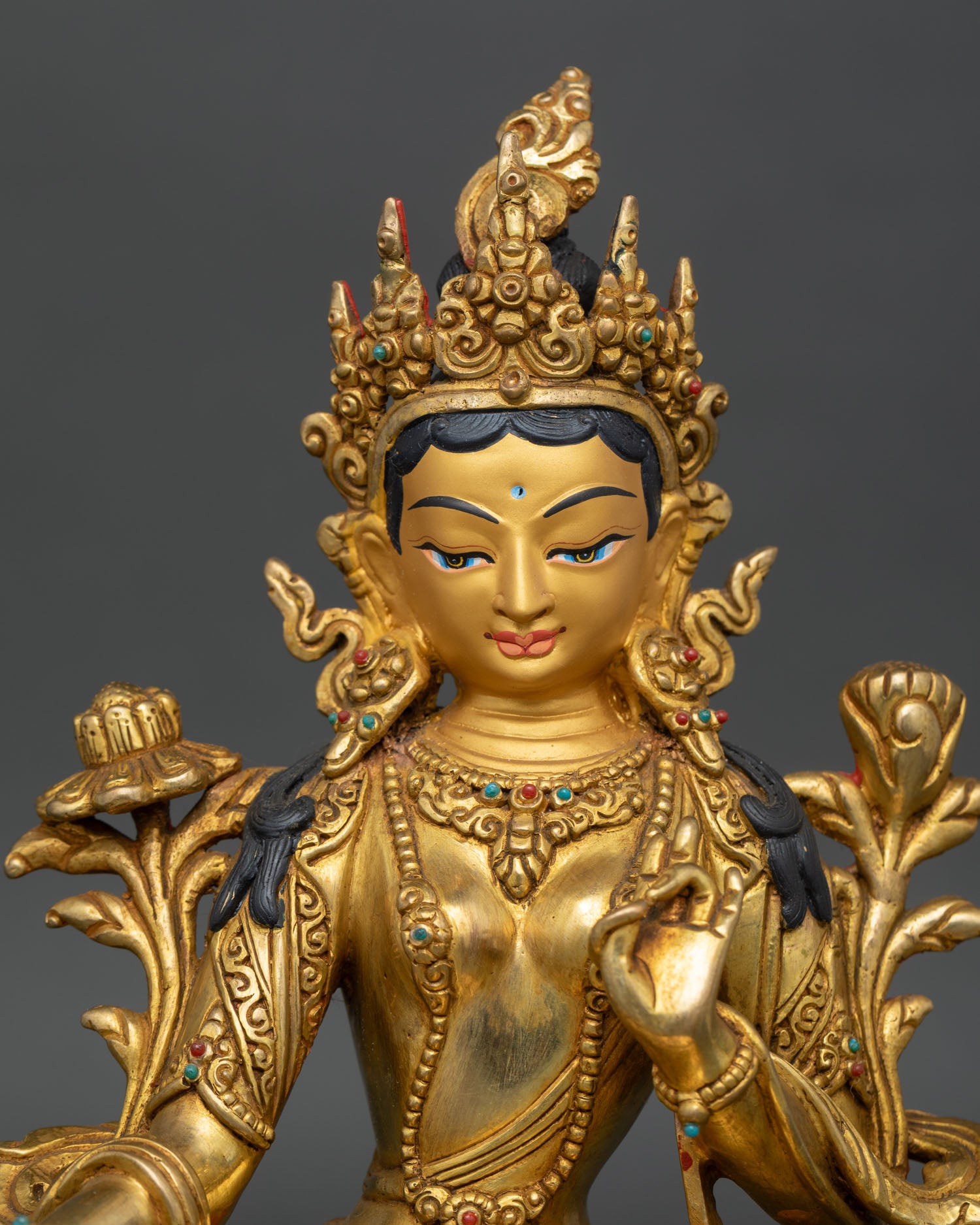 Close up Green Tara, gold-painted face, semi-precious stones, compassion deity