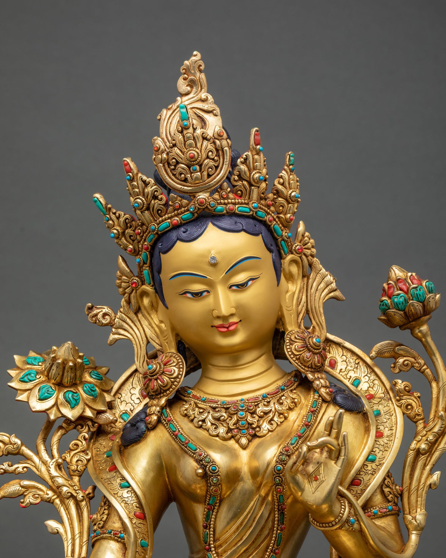 Close up Green Tara statue, gold painted, serene face, turquoise, coral stones, detailed Himalayan craftsmanship