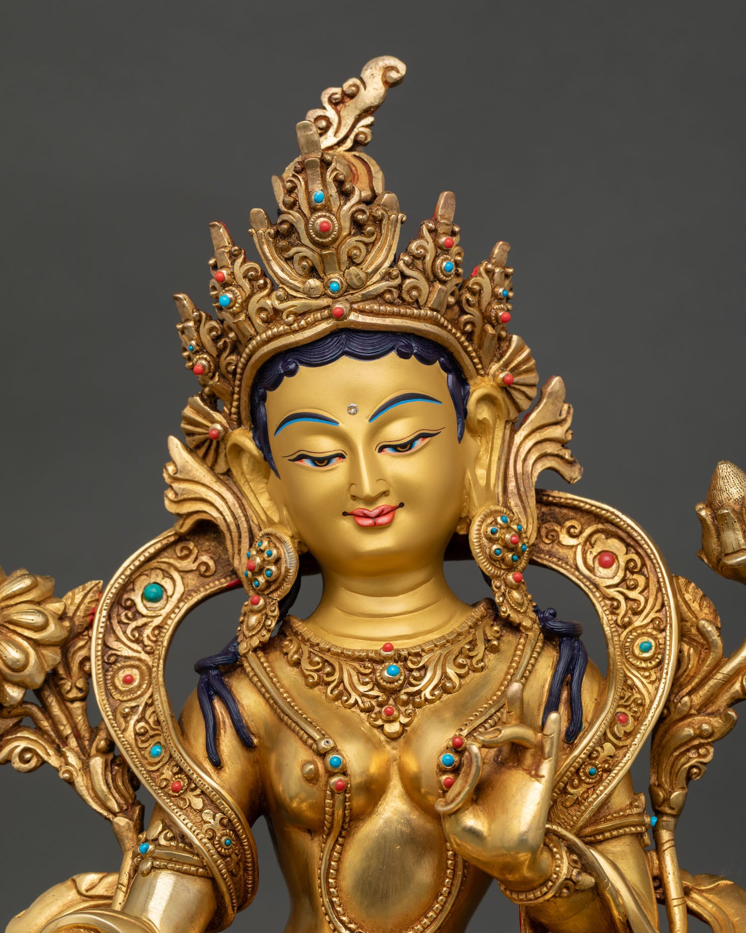 Close up green tara statue hand painted golden face with semi precious stones detailed facial expression buddhist goddess of compassion
