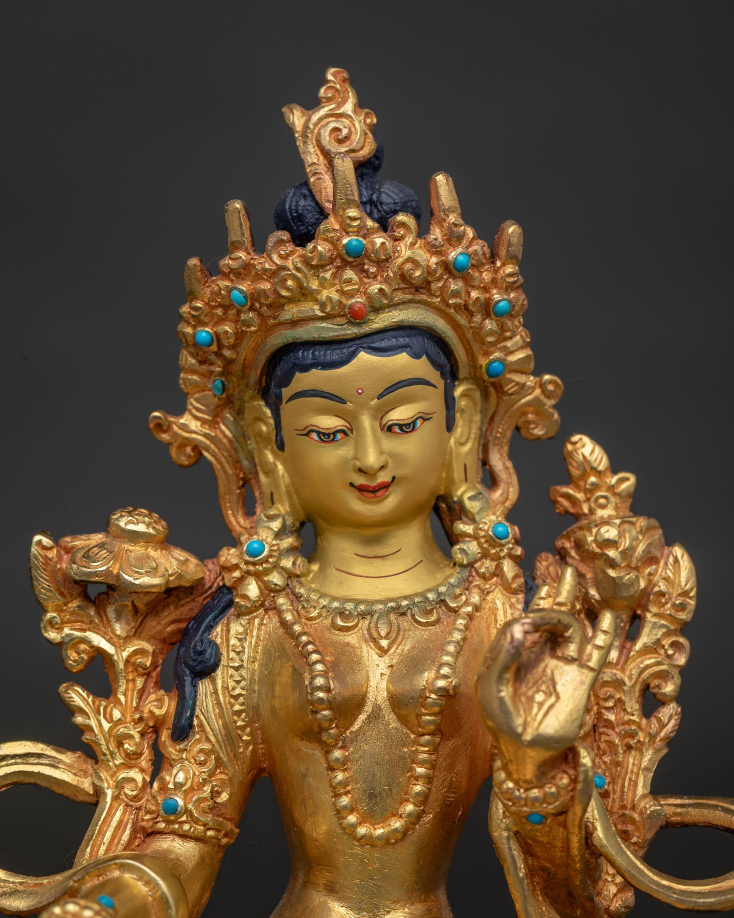 Close up Green Tara statue showing 24K gold painted face and semi precious stone details.