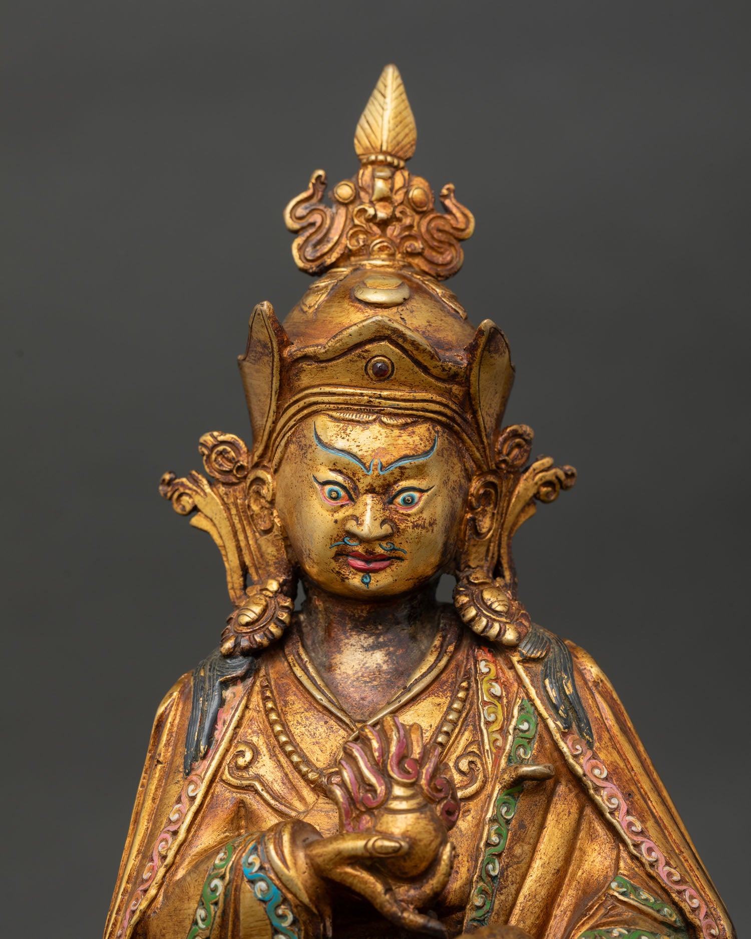close-up guru norlha statue showing gold painted face and intricate newari carvings
