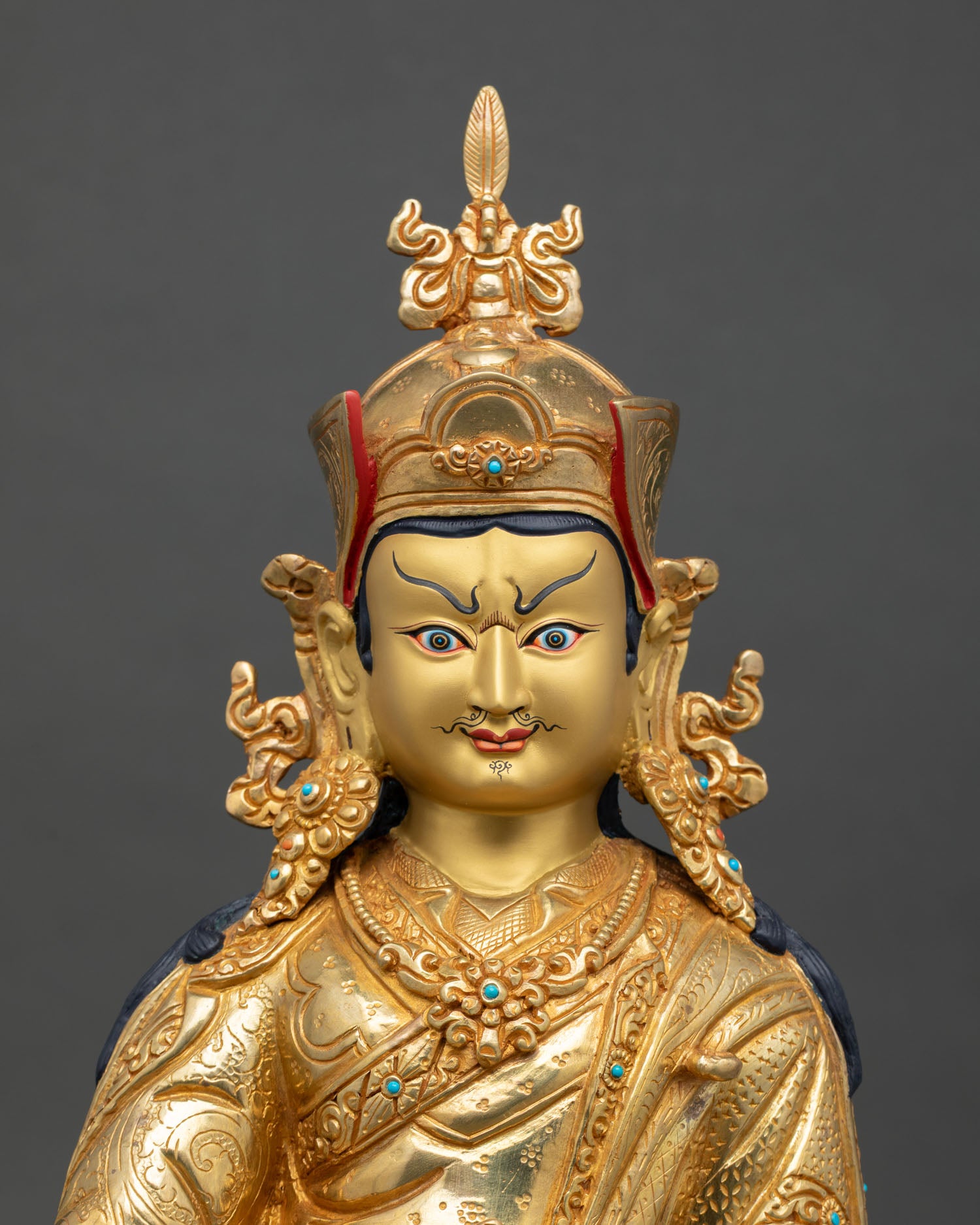 Close up view of Guru Padmasambhava statue showing gold painted face semi precious stone inlays and intricate engraved details