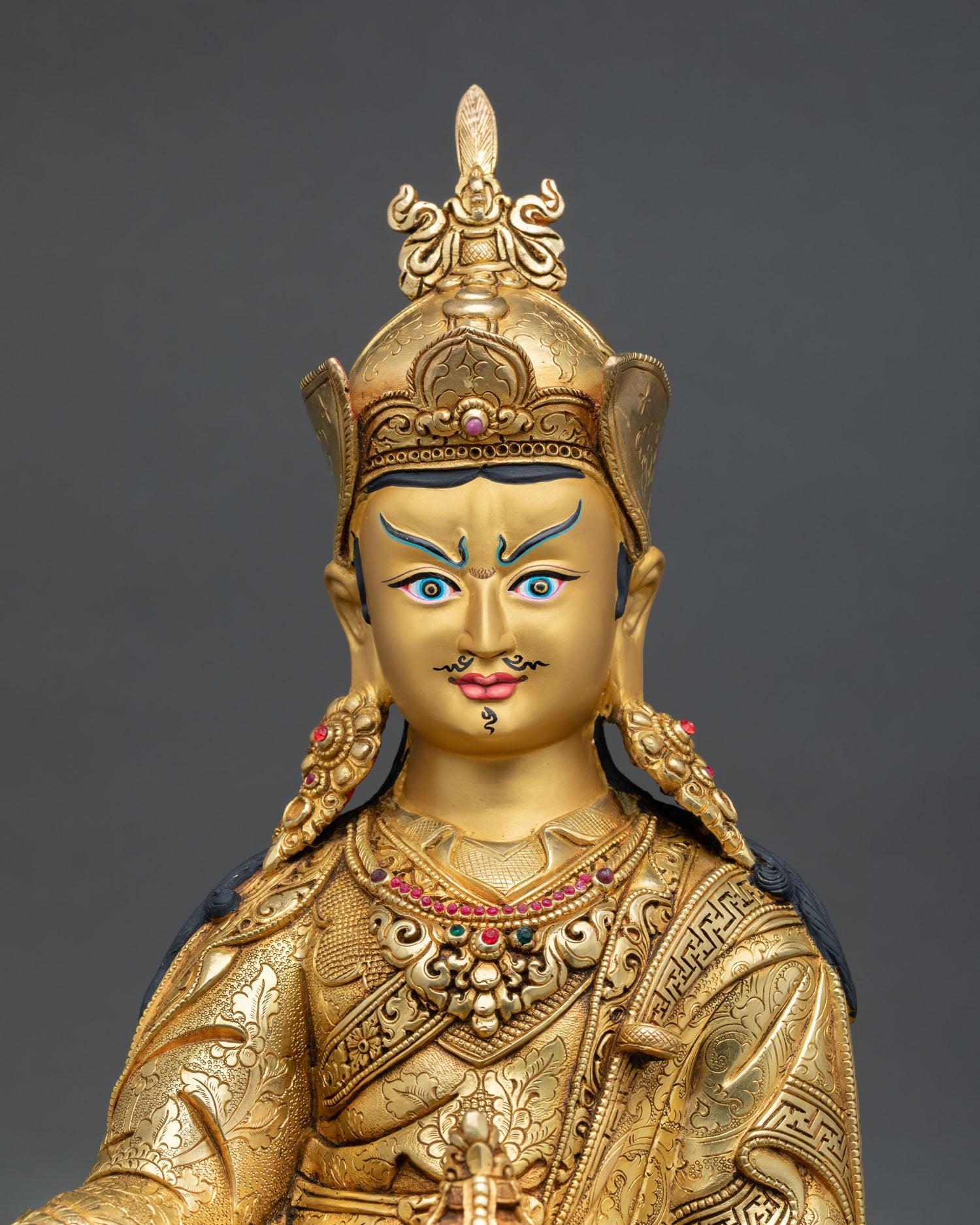 Close up Guru Rinpoche face with gold painted expression serene wisdom and Himalayan Newari artisan detailing