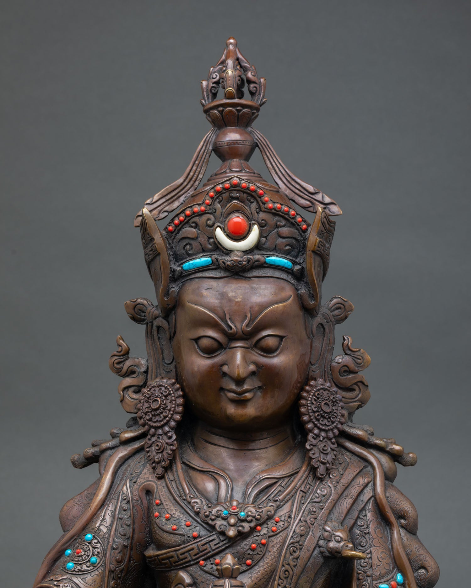 Close up Guru Rinpoche face with serene expression semi precious stone inlays
