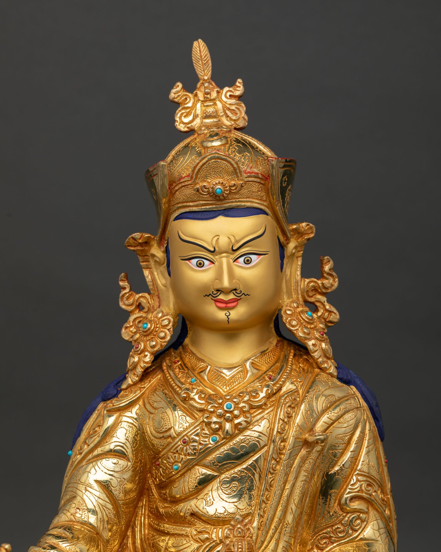 close up guru rinpoche padmasambhava statue showing gold painted face and sacred details