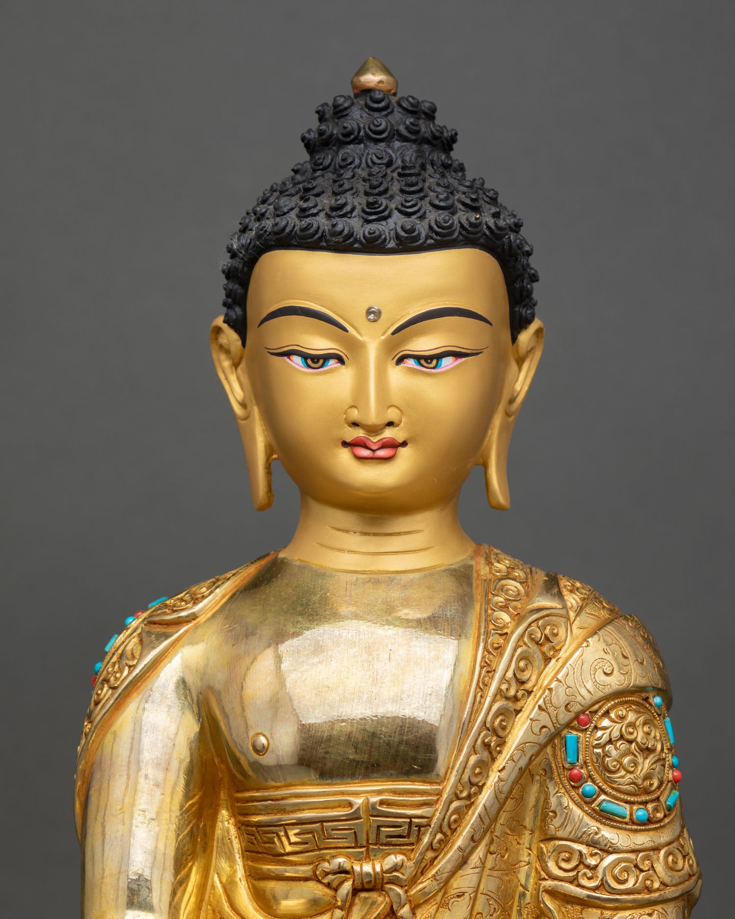 Close up Himalayan Shakyamuni Buddha statue with gold painted face semi precious stones detailed Newari craftsmanship Patan Nepal artwork