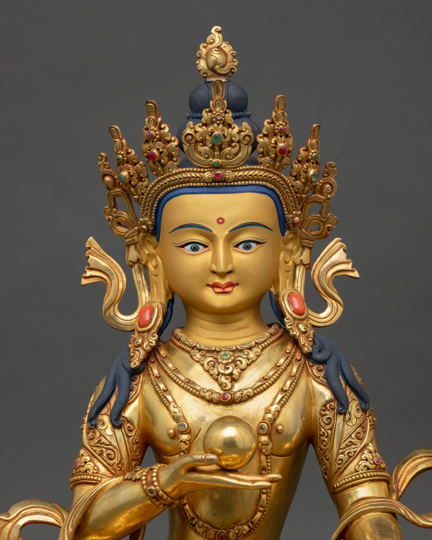 Close up Kshitigarbha Bodhisattva statue showing gold painted face semi precious stone detailing and intricate lost wax Nepalese craftsmanship from Patan, Nepal.