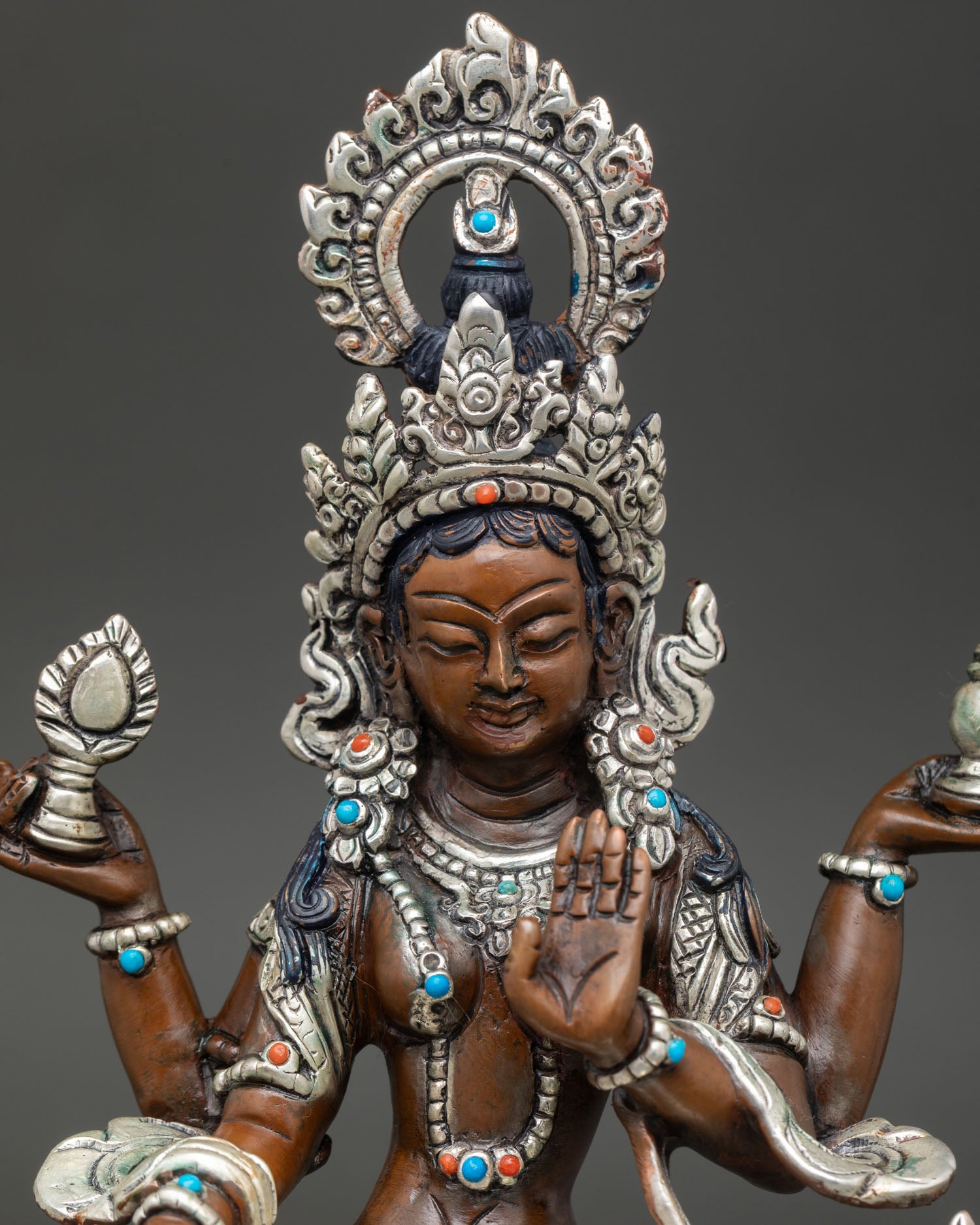 Close up Lakshmi statue ornate crown semi precious stones four hands holding lotus flower and pot of gold Hindu deity sculpture