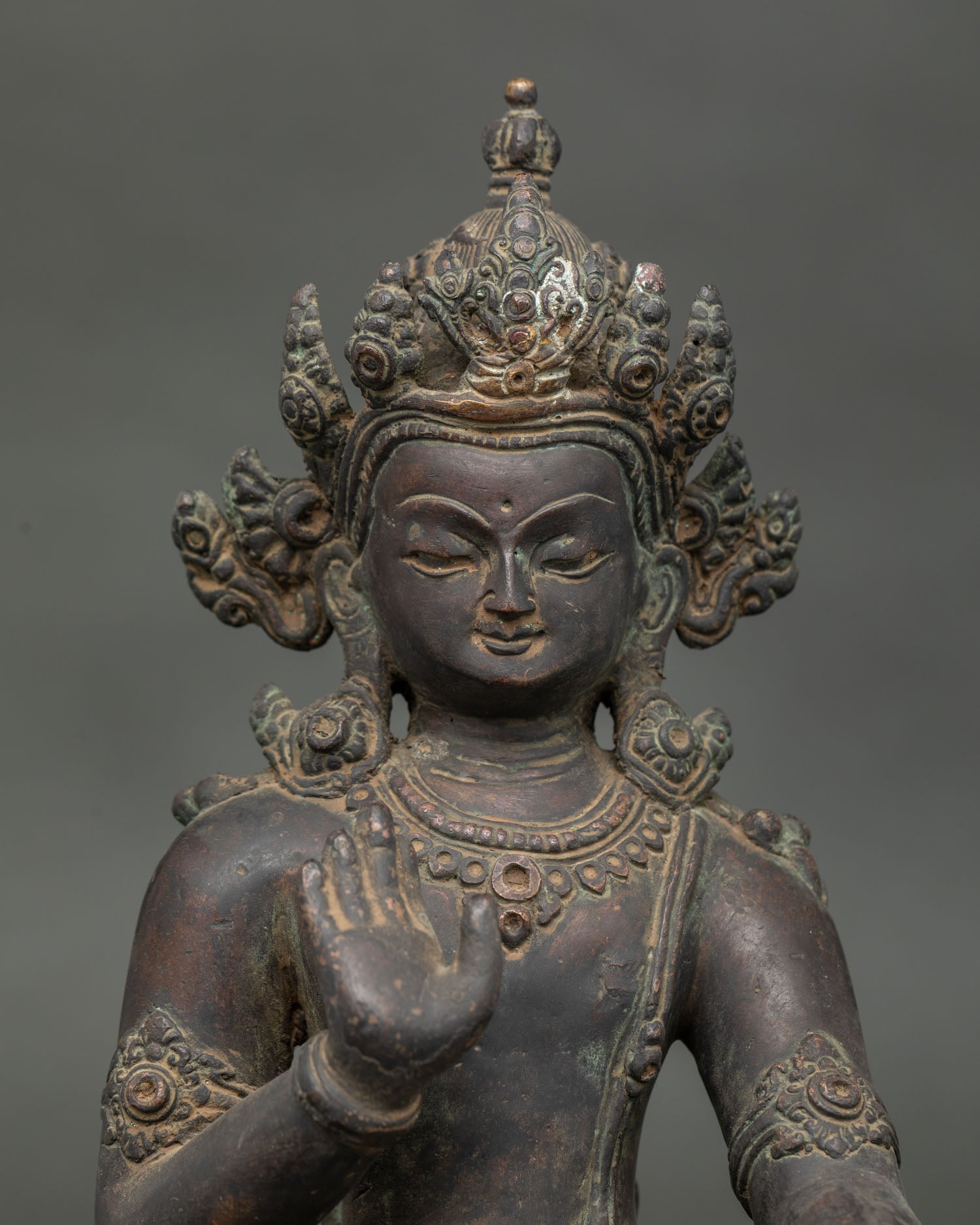 Close up Lokeshvara statue showing Abhaya Mudra and detailed antique copper finish.