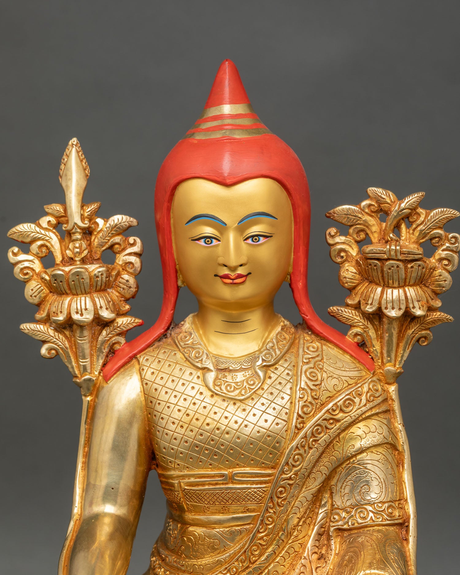 Close up of Longchenpa face with pandita hat, serene expression, and gold painted details.