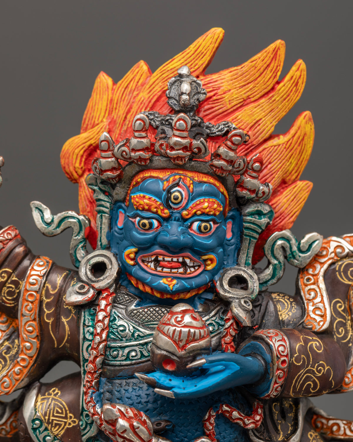 Close up mahakala bernagchen statue with fierce face and ornate details.