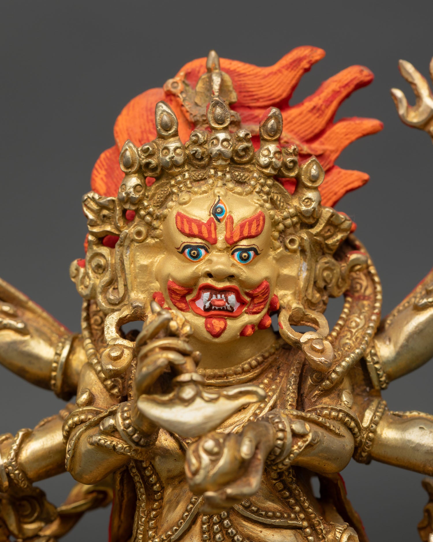 Close up Mahakala statue showing third eye gold painted face bared fangs, Himalayan craftsmanship.