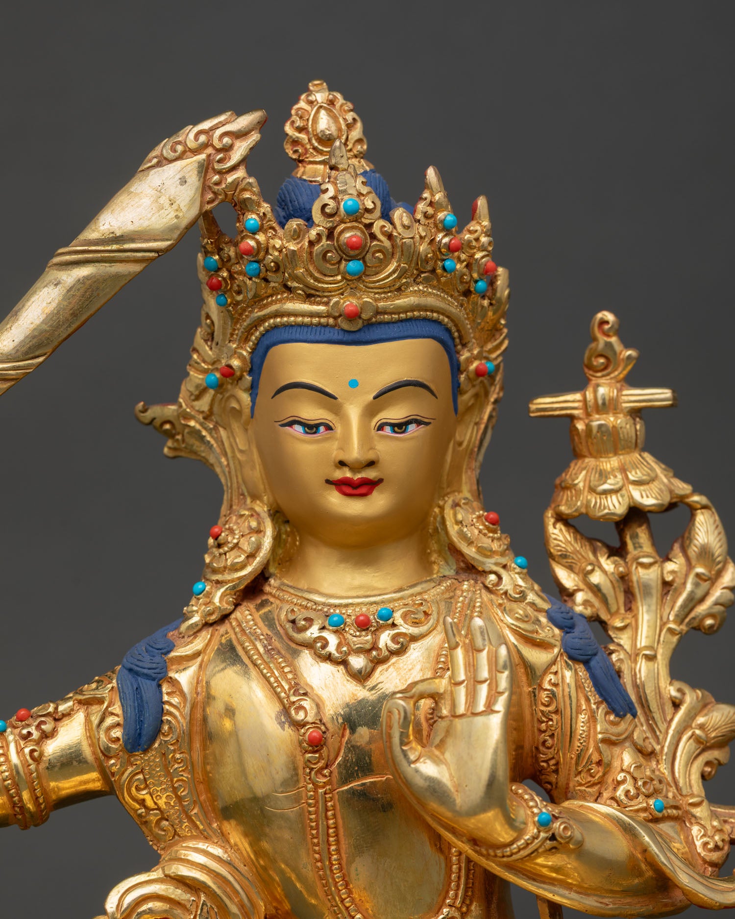Close Up Manjushree Statue gold painted face semi precious stones flaming sword of wisdom Buddhist spiritual sculpture detail