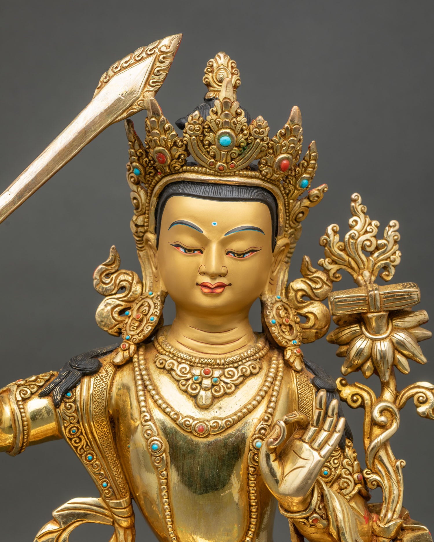 Close up of Manjushri face with golden painted details and semi precious stones