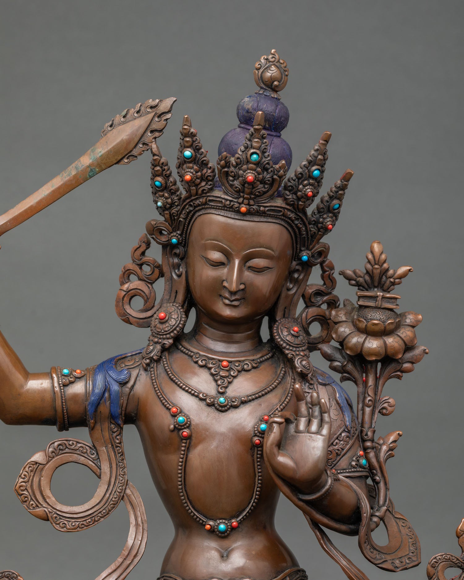 Close-up of Manjushri statue showing flaming sword and lotus-supported Prajnaparamita scripture.