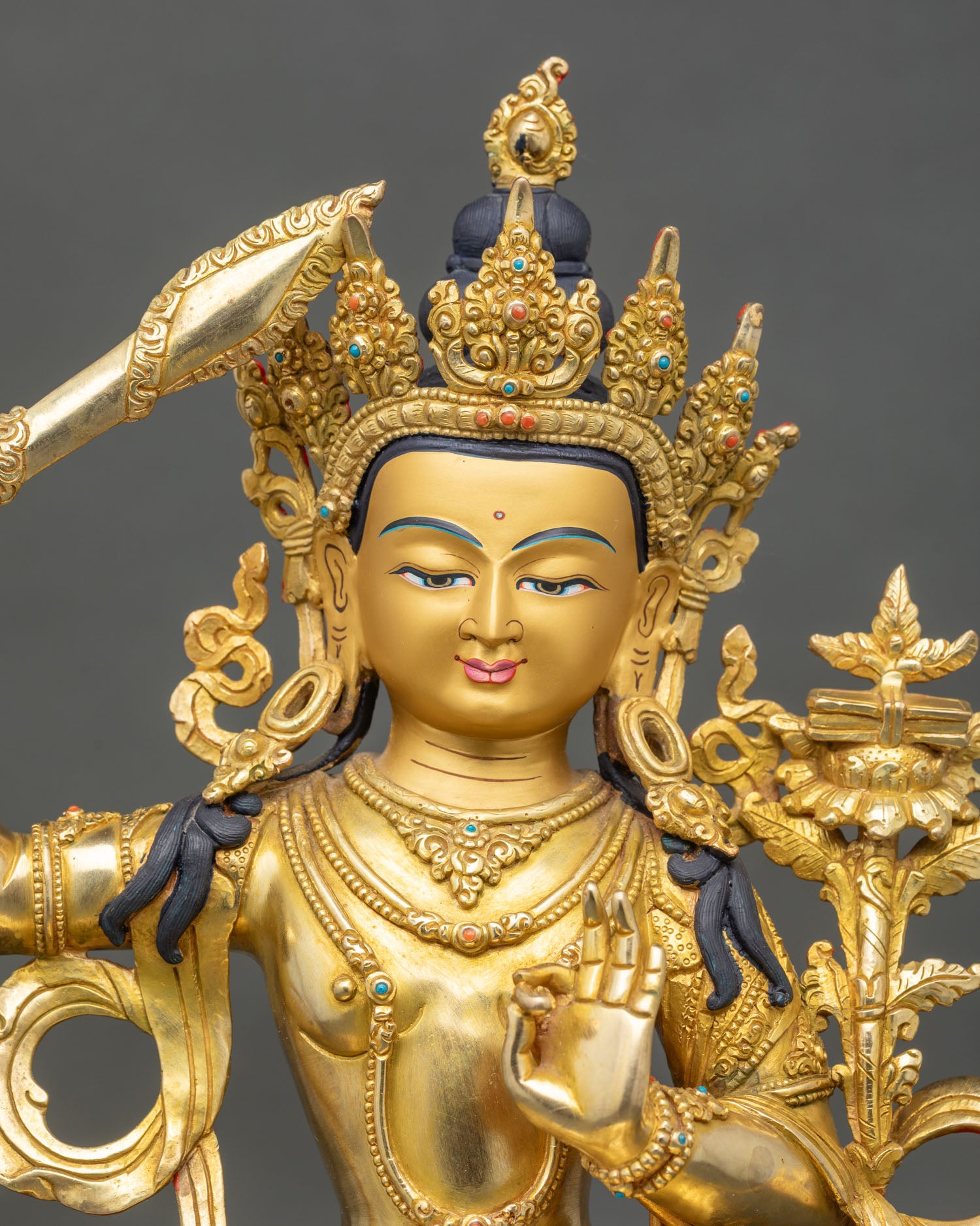 Close up of Manjushri statue flaming sword Prajnaparamita scripture gold painted face intricate carvings lotus pedestal