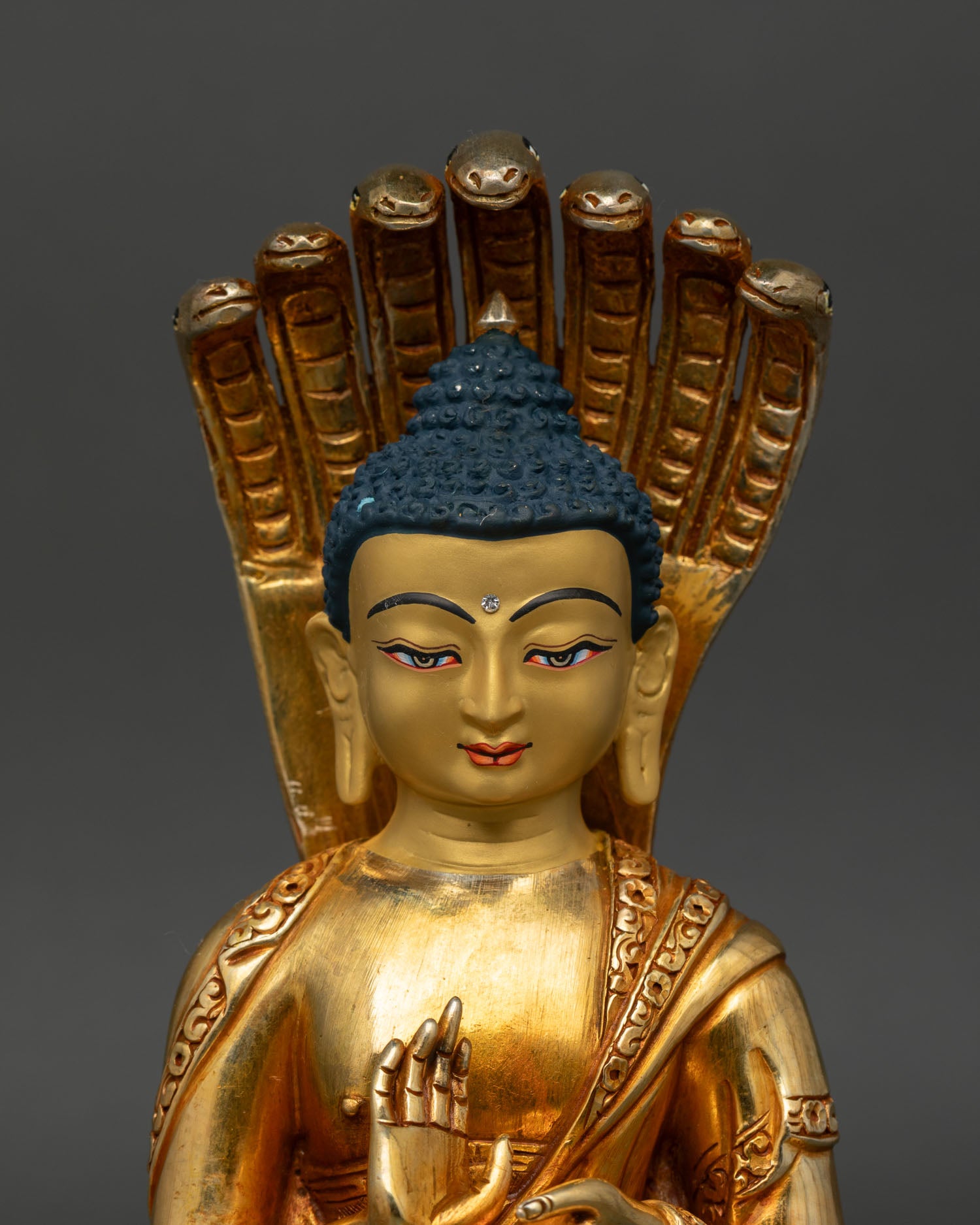close up nagarjuna face detail naga halo coiled serpent radiant gold buddhist sculpture