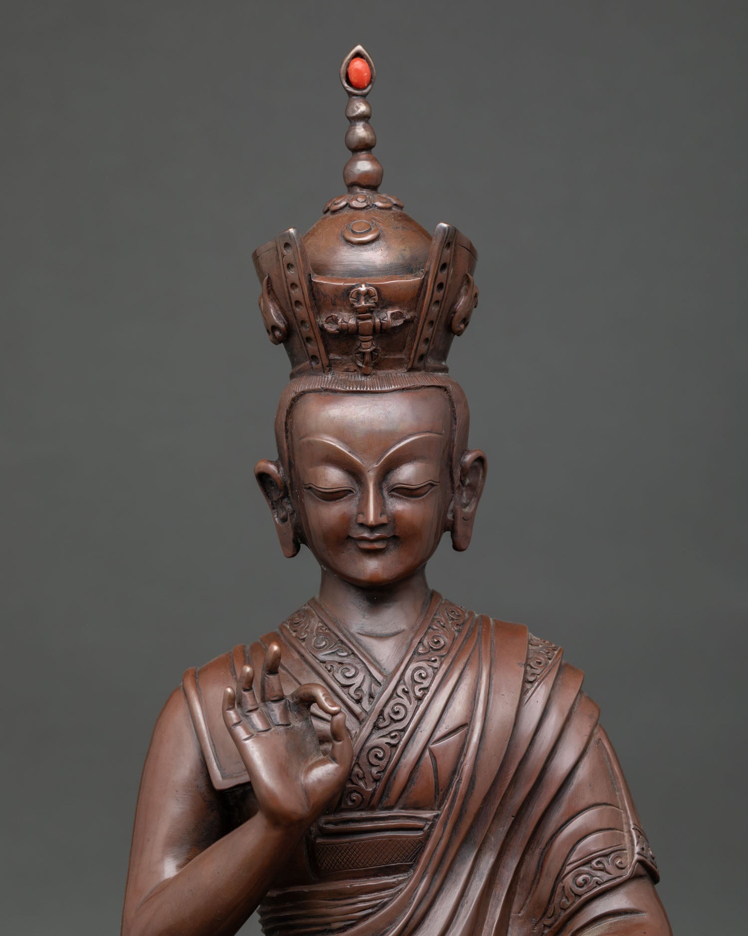 Close-up of 16th Karmapa statue showing serene expression, red coral finial on Black Crown, and intricate Newari craftsmanship