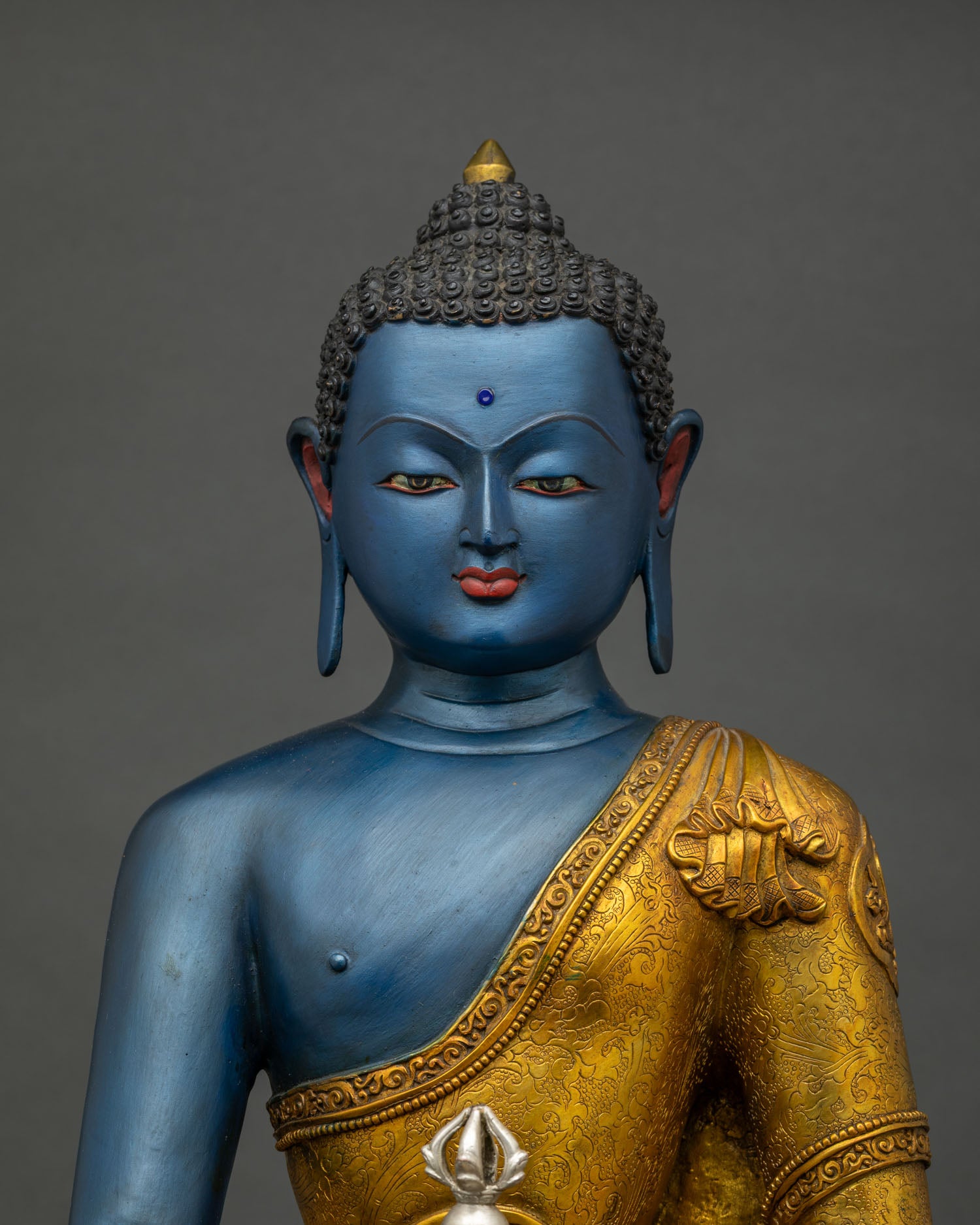 Close up of Akshobhya Buddha statue showing gold gilded robe and blue complexion detailing