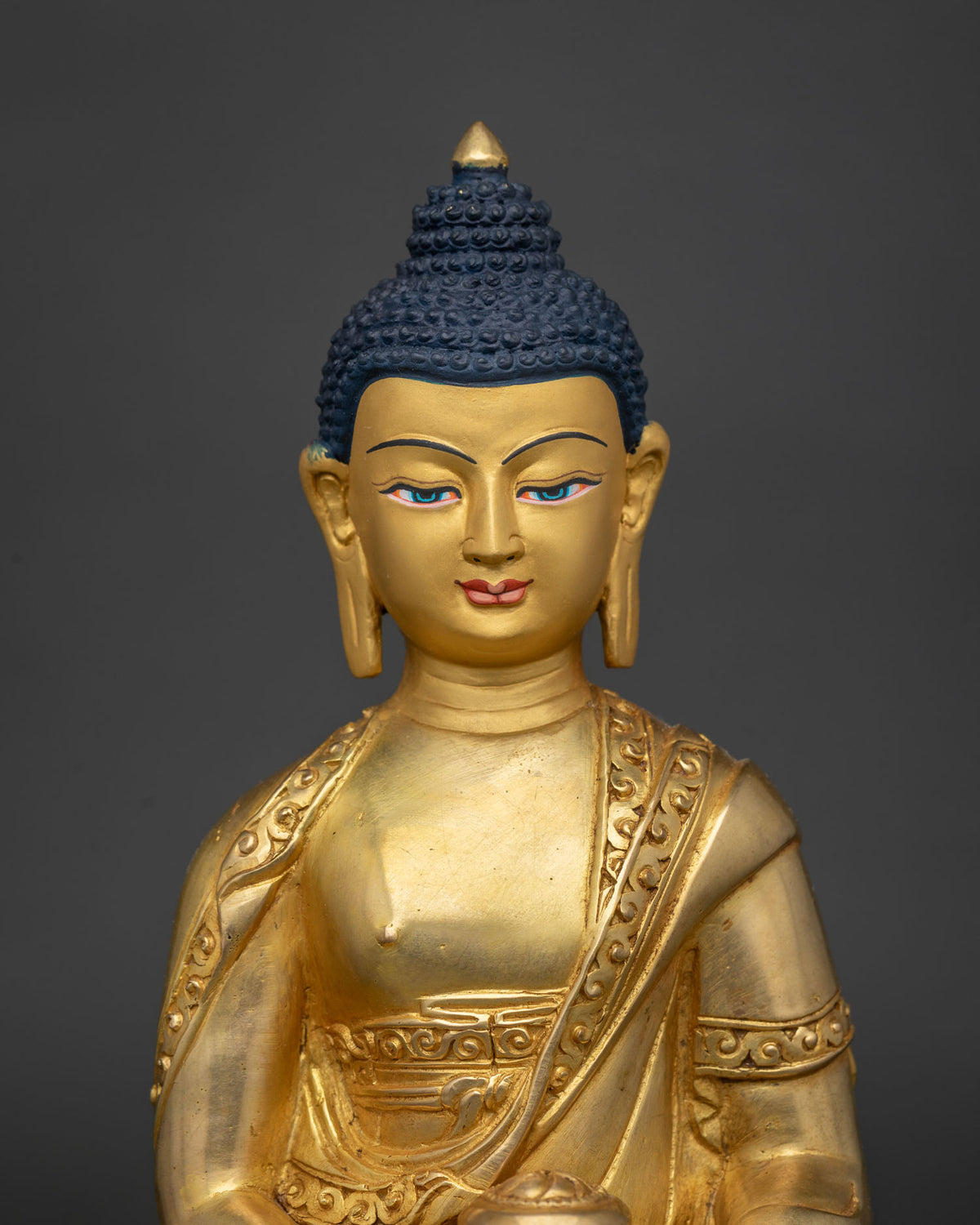 Close up of Amitabha Buddha statue in dhyana mudra holding an alms bowl, gold fire-gilded copper