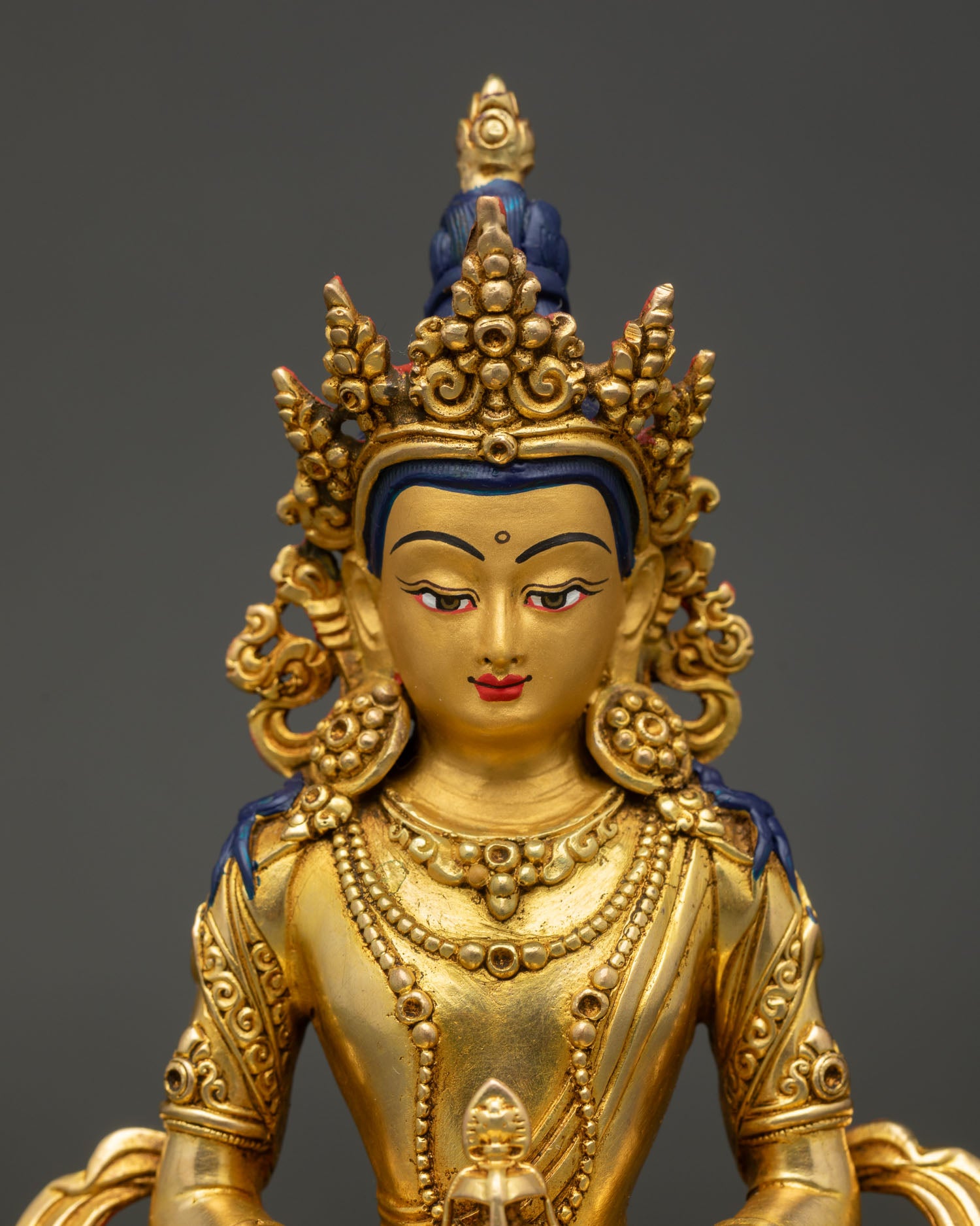 Close-up of Amitayus statue holding longevity vase, gold-painted face, and fine details