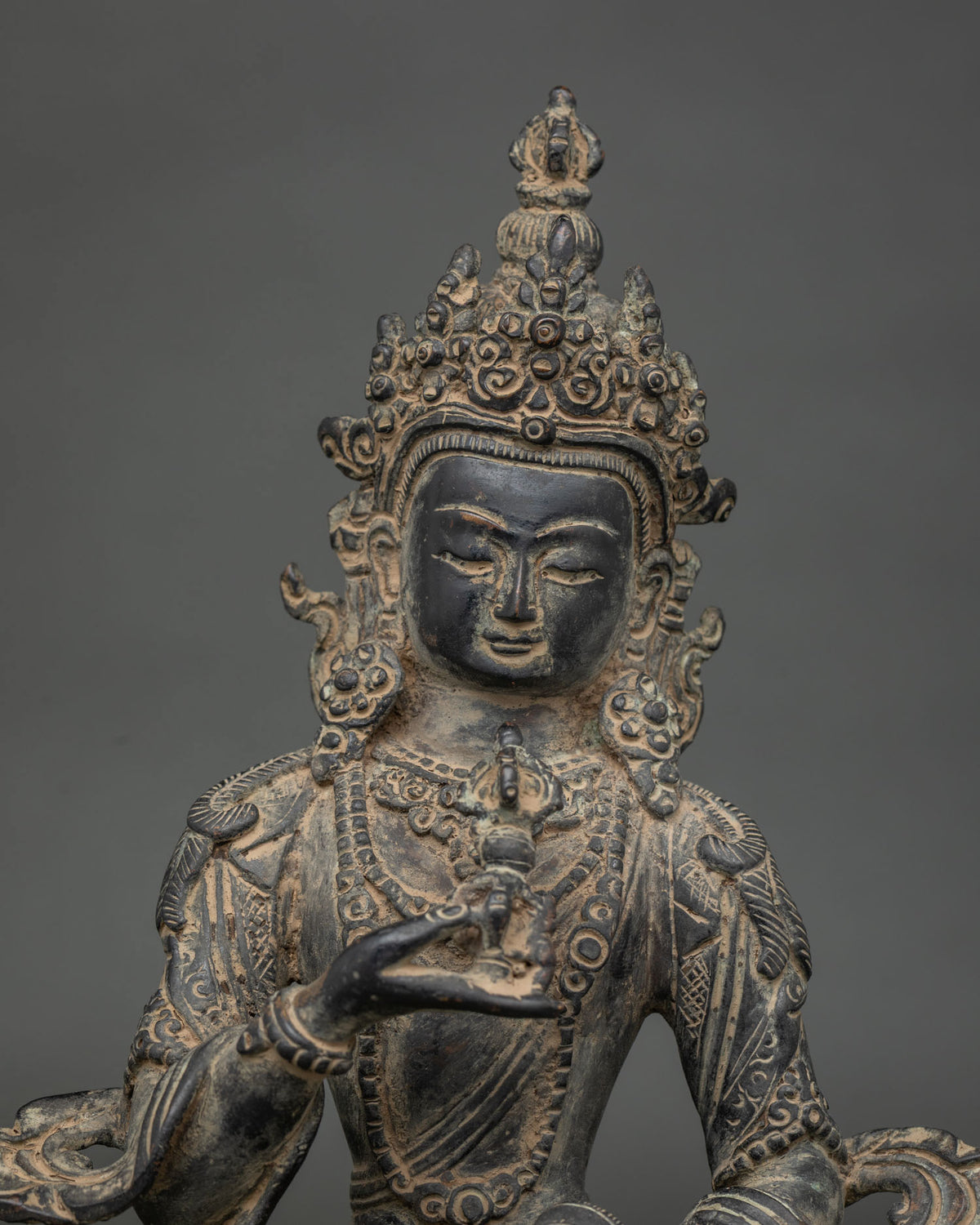 Close-up of antique finish Vajrasattva statue with ornate crown, serene face and vajra in hand