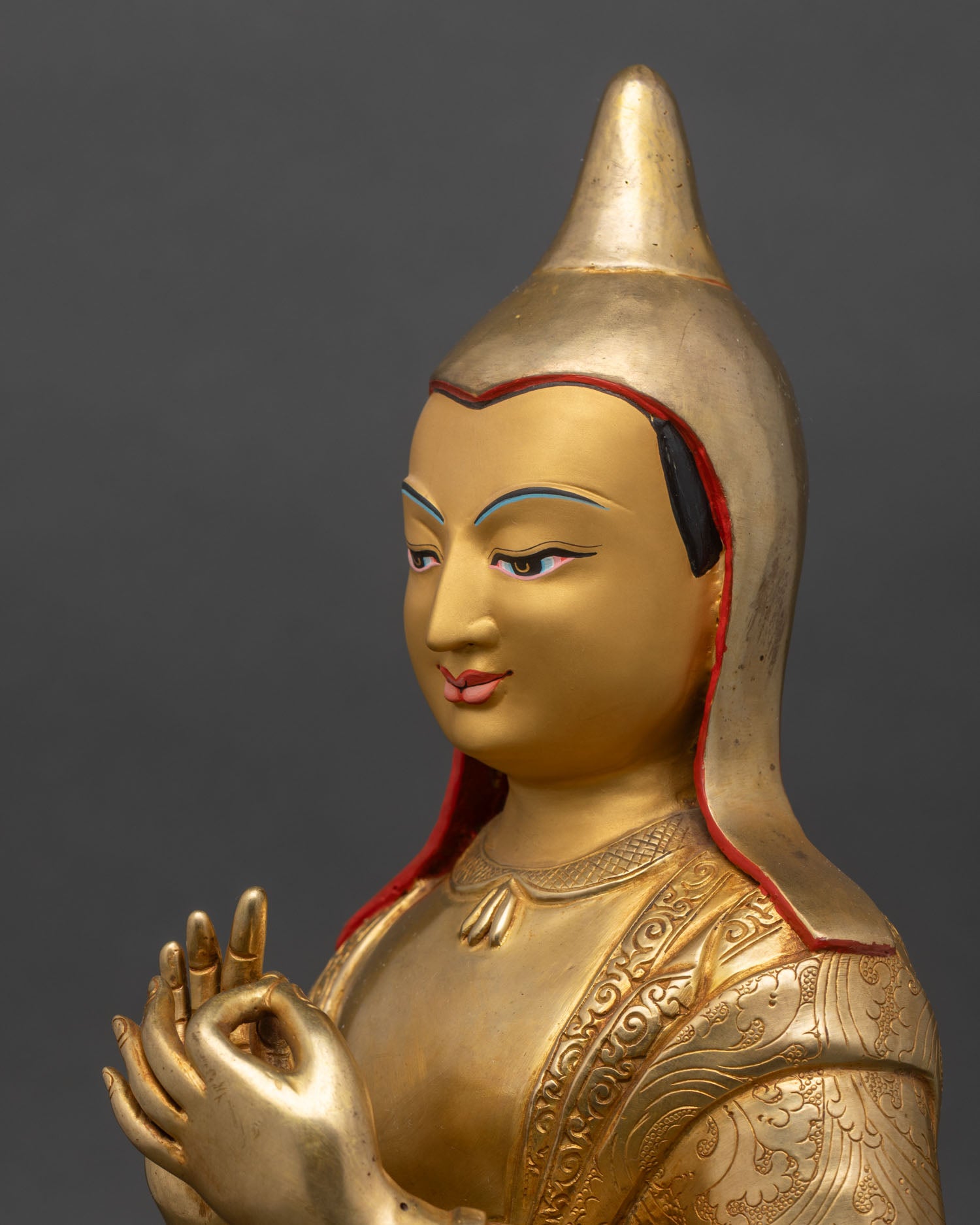 Close up of Atisha statue gold painted face pandit hat dharmachakra mudra