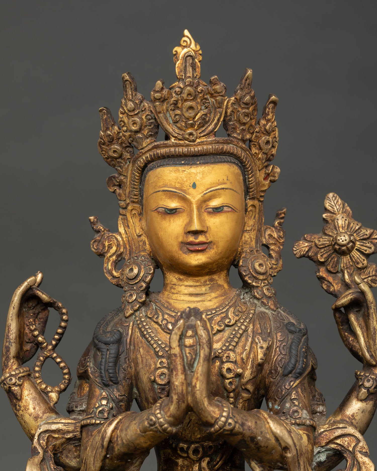 Close up of Avalokiteshvara statue face showing gold gilded details and compassionate expression