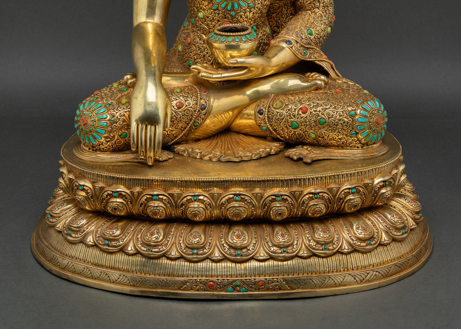Close-up of Bhumisparsha mudra hand and alms bowl on lotus throne