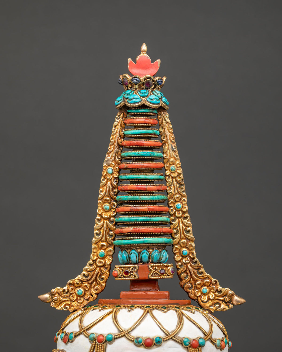 Close-up of Buddhist stupa spire with turquoise and coral rings and sun moon finial, copper chorten
