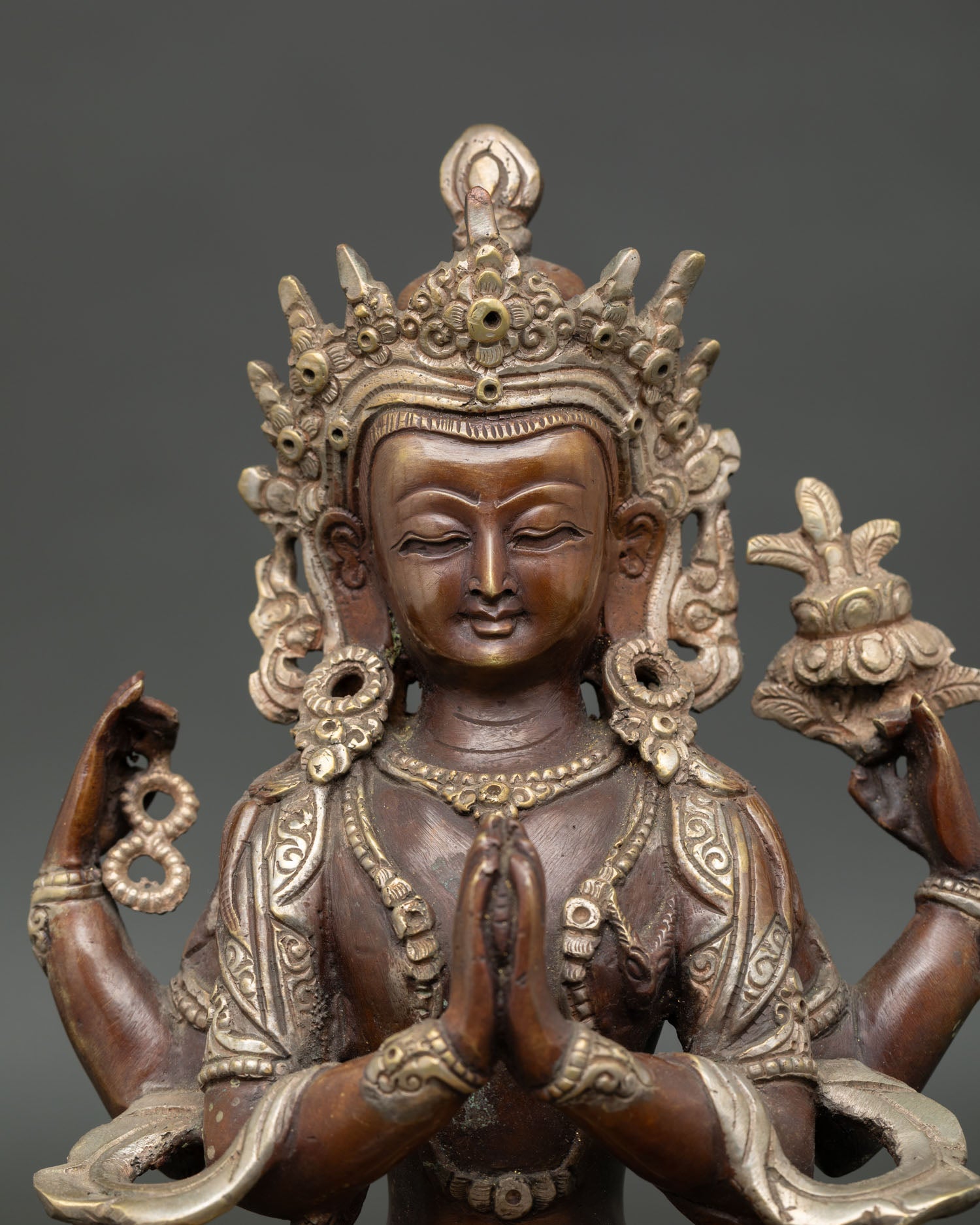 close up of chenrezig bodhisattva statue showing antique oxidized copper details