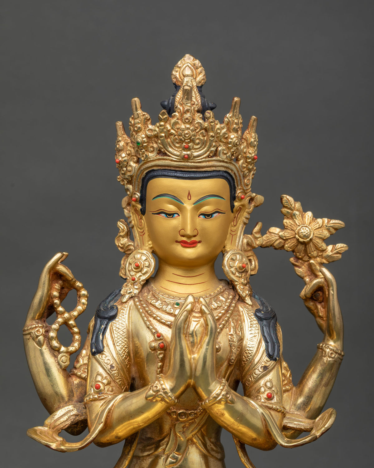 Close-up of Chenrezig face and crown with gold pigment details, mala and lotus flower
