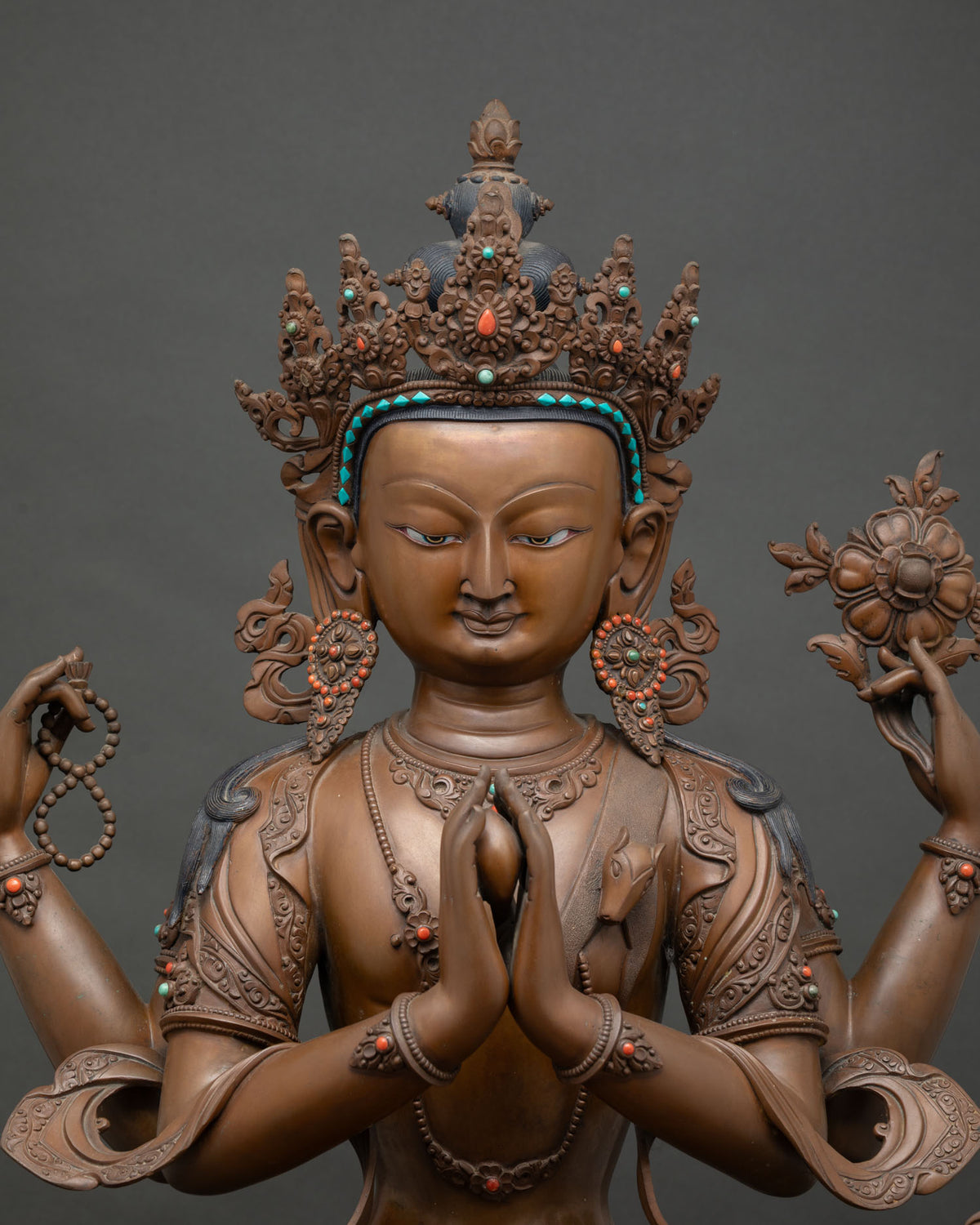 Close-up of Chenrezig's four hands showing anjali mudra, rosary, and lotus stem