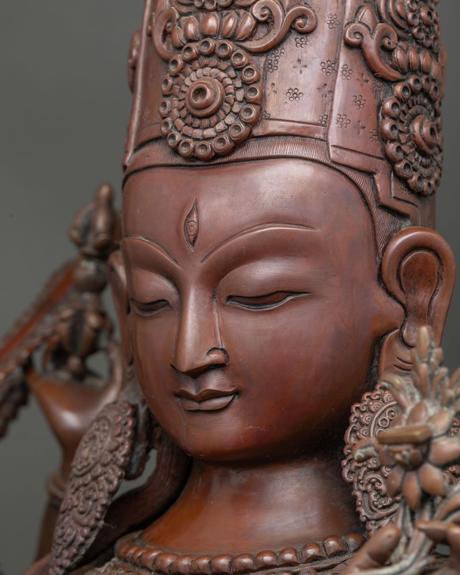 Close-up of Chundi Juntei Kannon's serene face and jeweled crown, oxidized copper statue