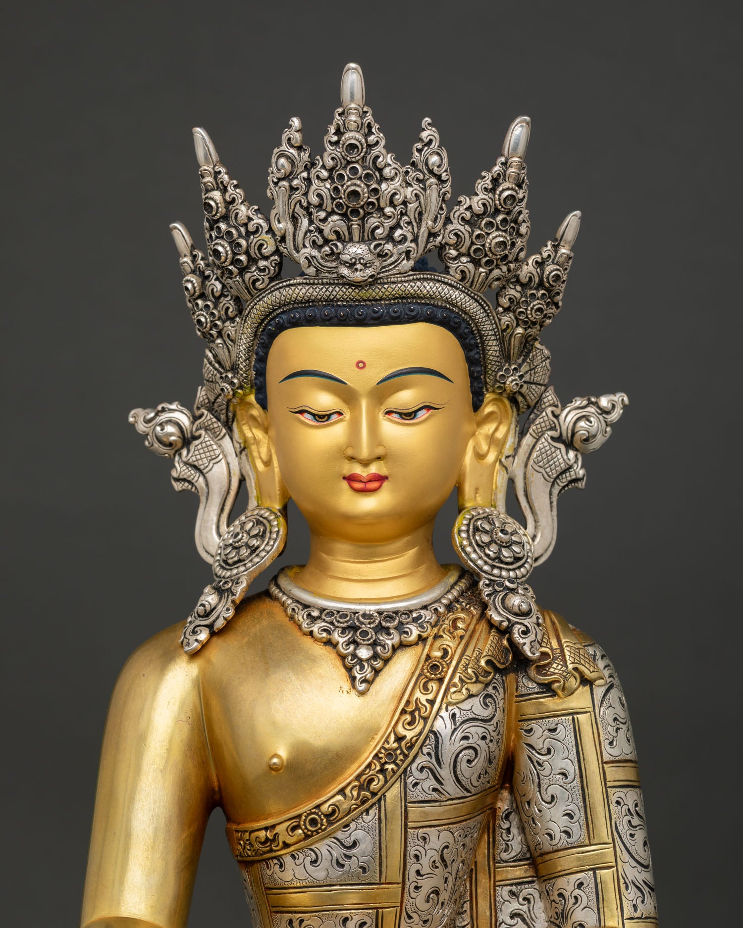 close up of crowned shakyamuni buddha statue with intricate crown and robe details