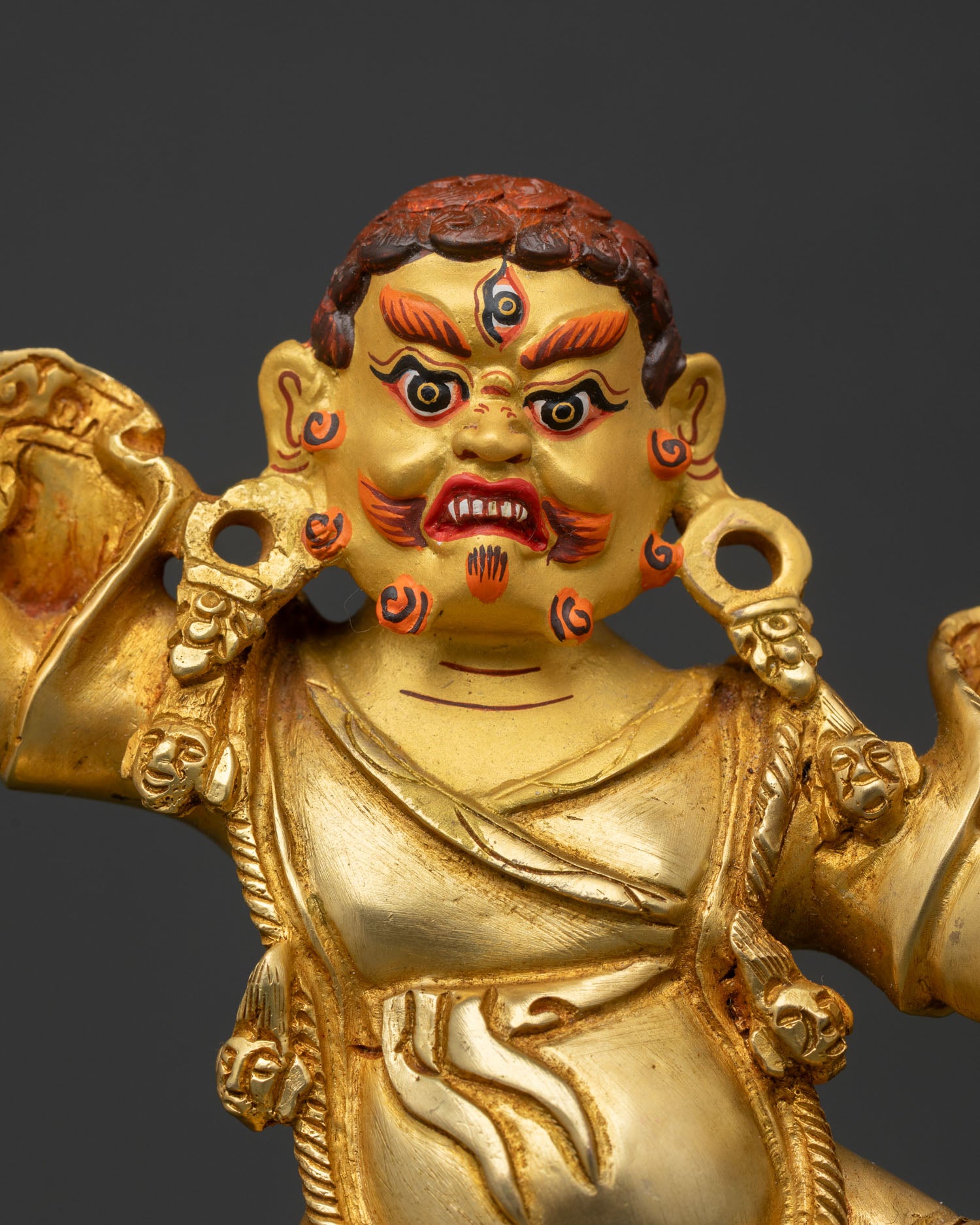 Close Up of Dorje Drolo Statue with Gold Painted Face Fierce Expression and Raised Dorje