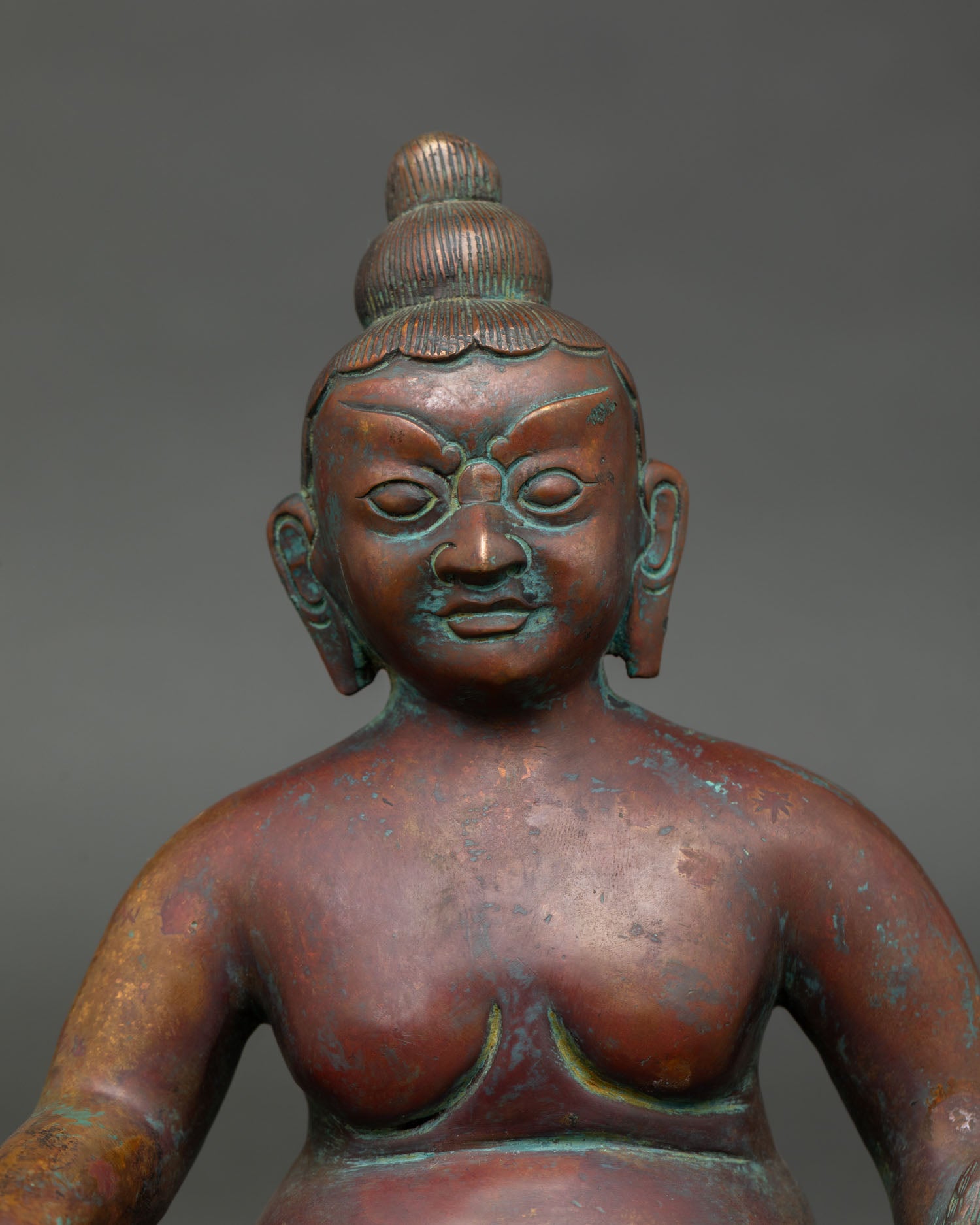 close-up of dzambhala statue face with detailed copper craftsmanship and antique finish