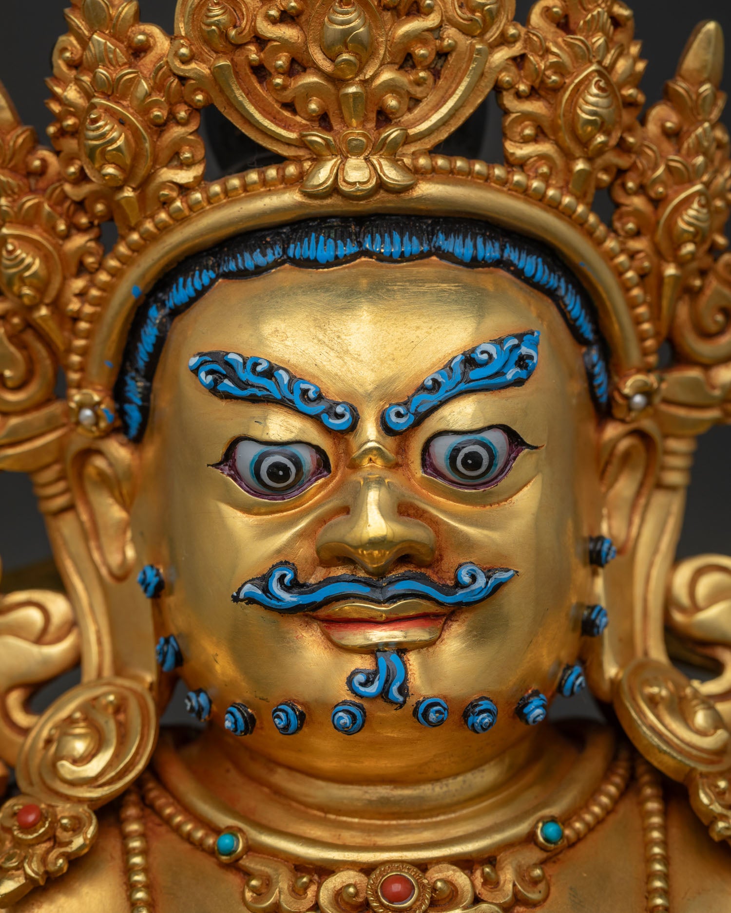 Close-up of Dzambhala statue's face with hand-painted eyes, brows and mustache