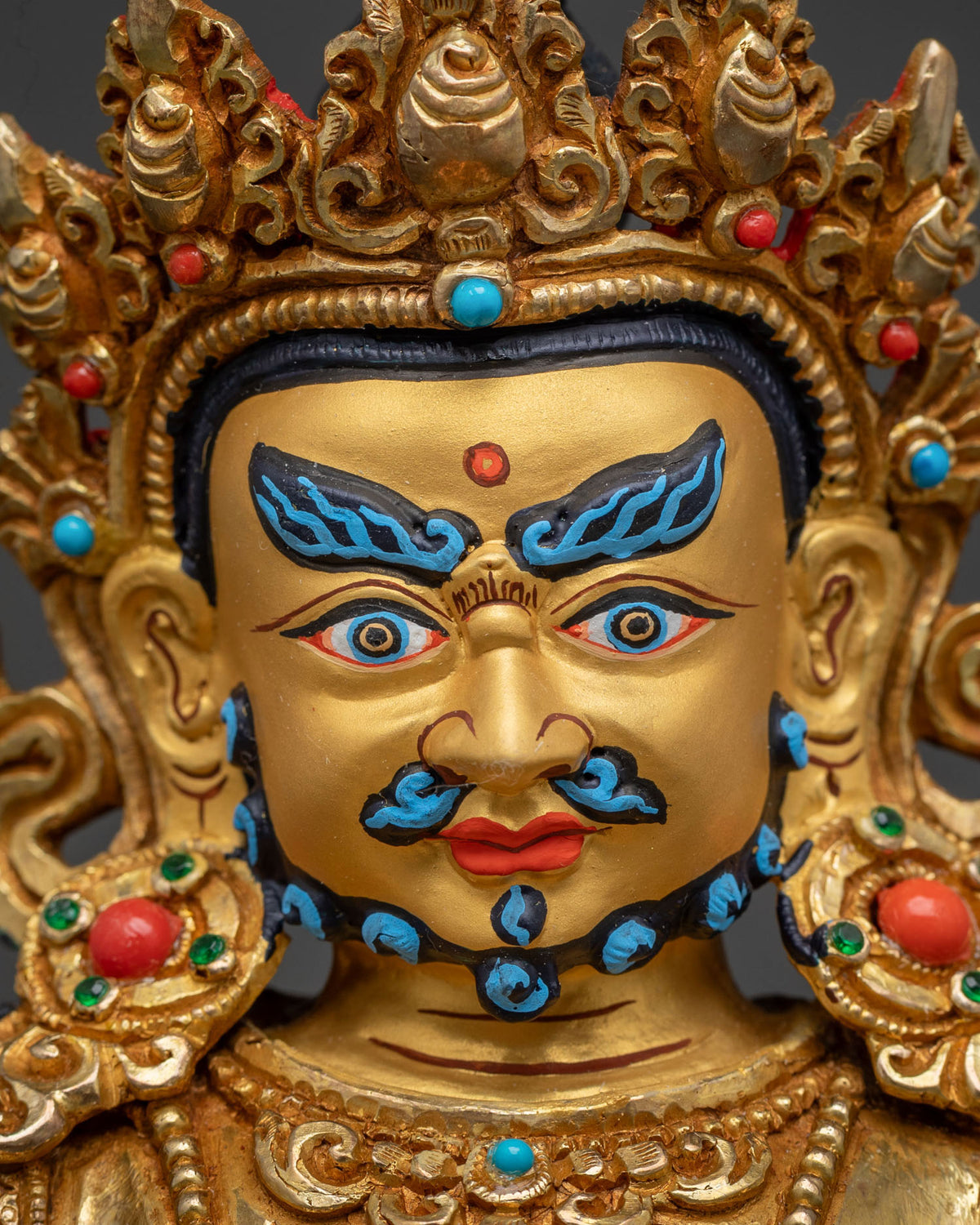 Close up of Dzambhala statue showing five jewel crown earrings and layered necklaces.