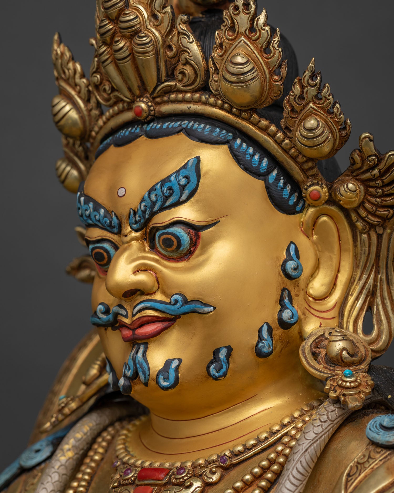 Close-up of Dzambhala Statue's face with gold crown and blue painted brows