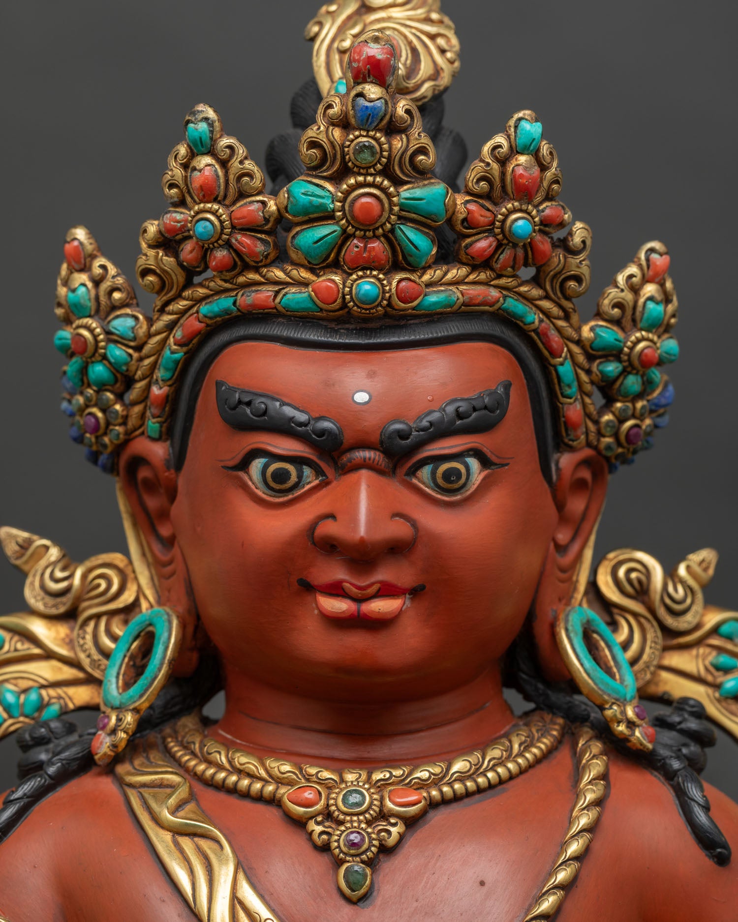 Close-up of Dzambhala's face – hand-painted Nepalese Buddhist wealth deity statue detail